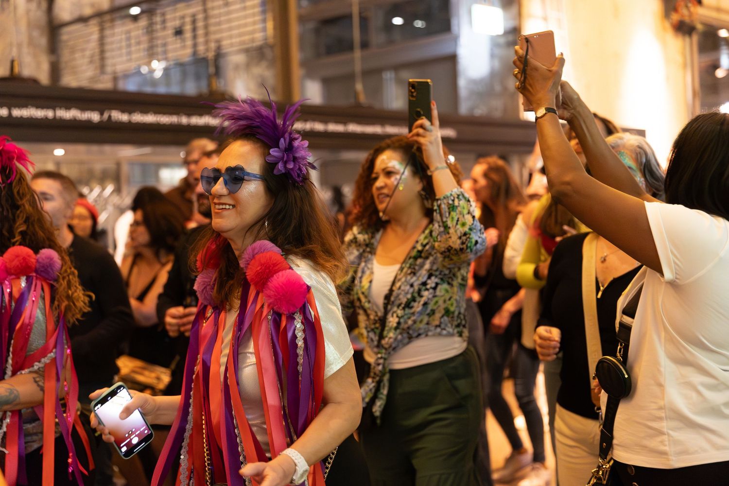 Celebratory crowd dances and raises hands during an indoor music event.