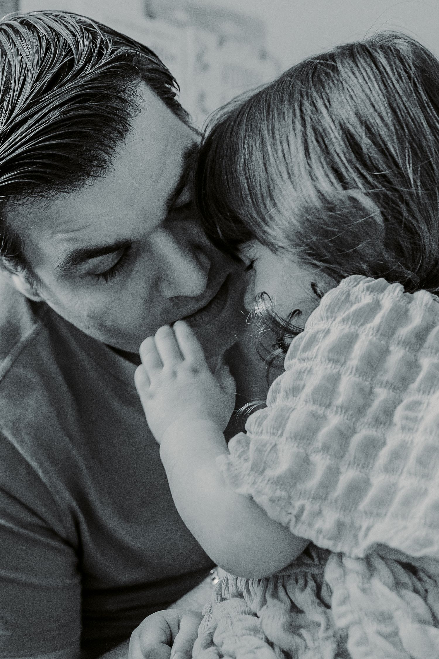 Intimate black and white portrait showing tender moment between parent and child.