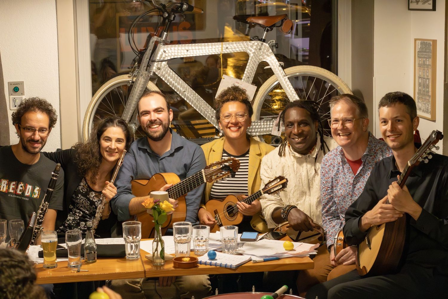 Musicians with various string instruments gather around table for casual jam session.
