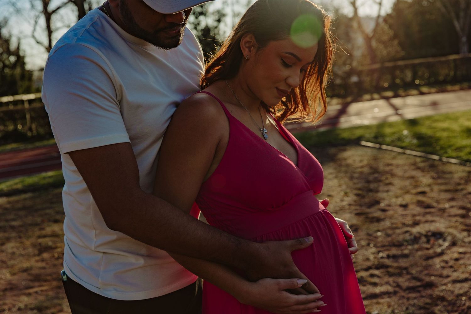 Intimate outdoor maternity photoshoot silhouetted against golden sunlight.