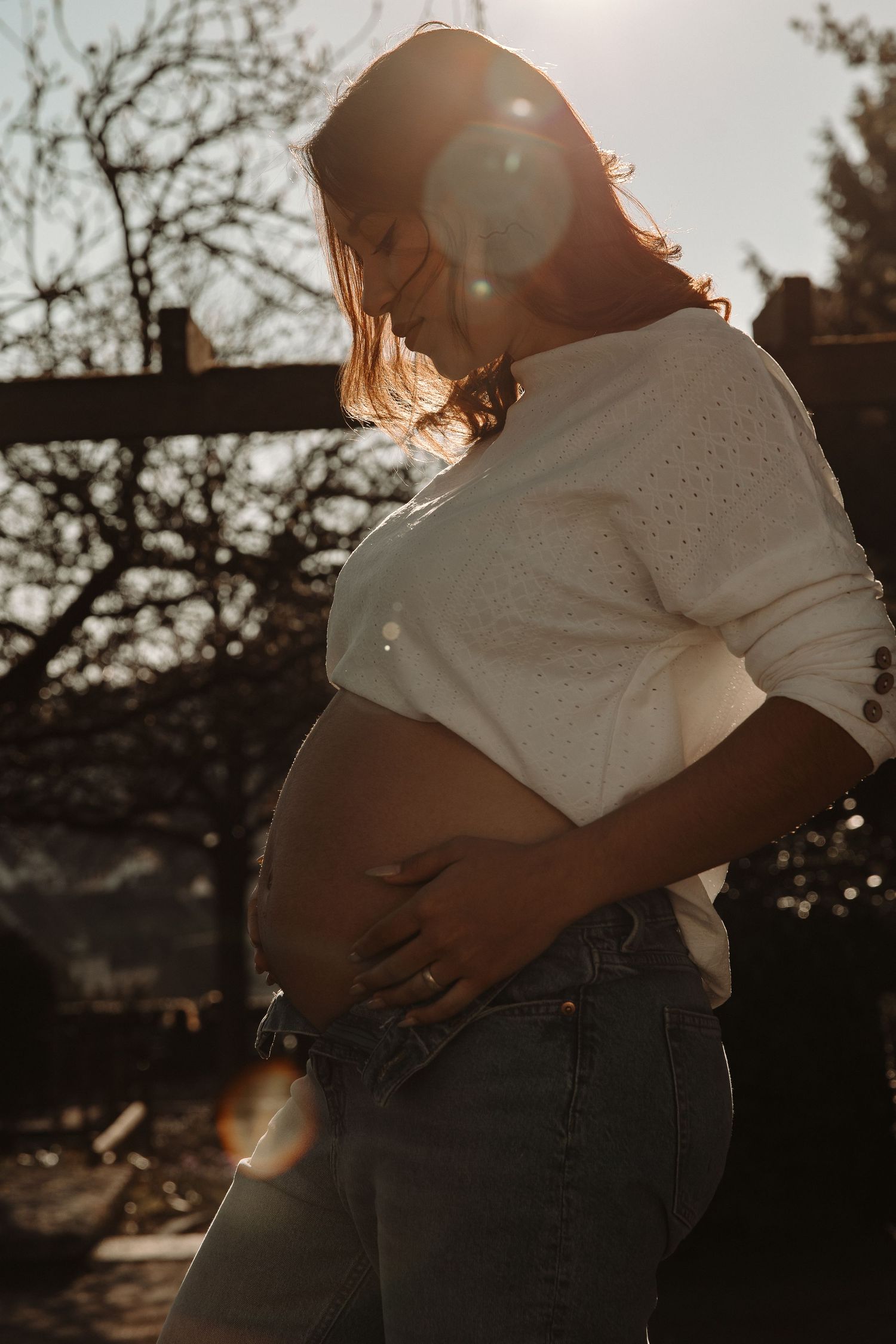 Backlit maternity portrait showing silhouette against golden sunset light.