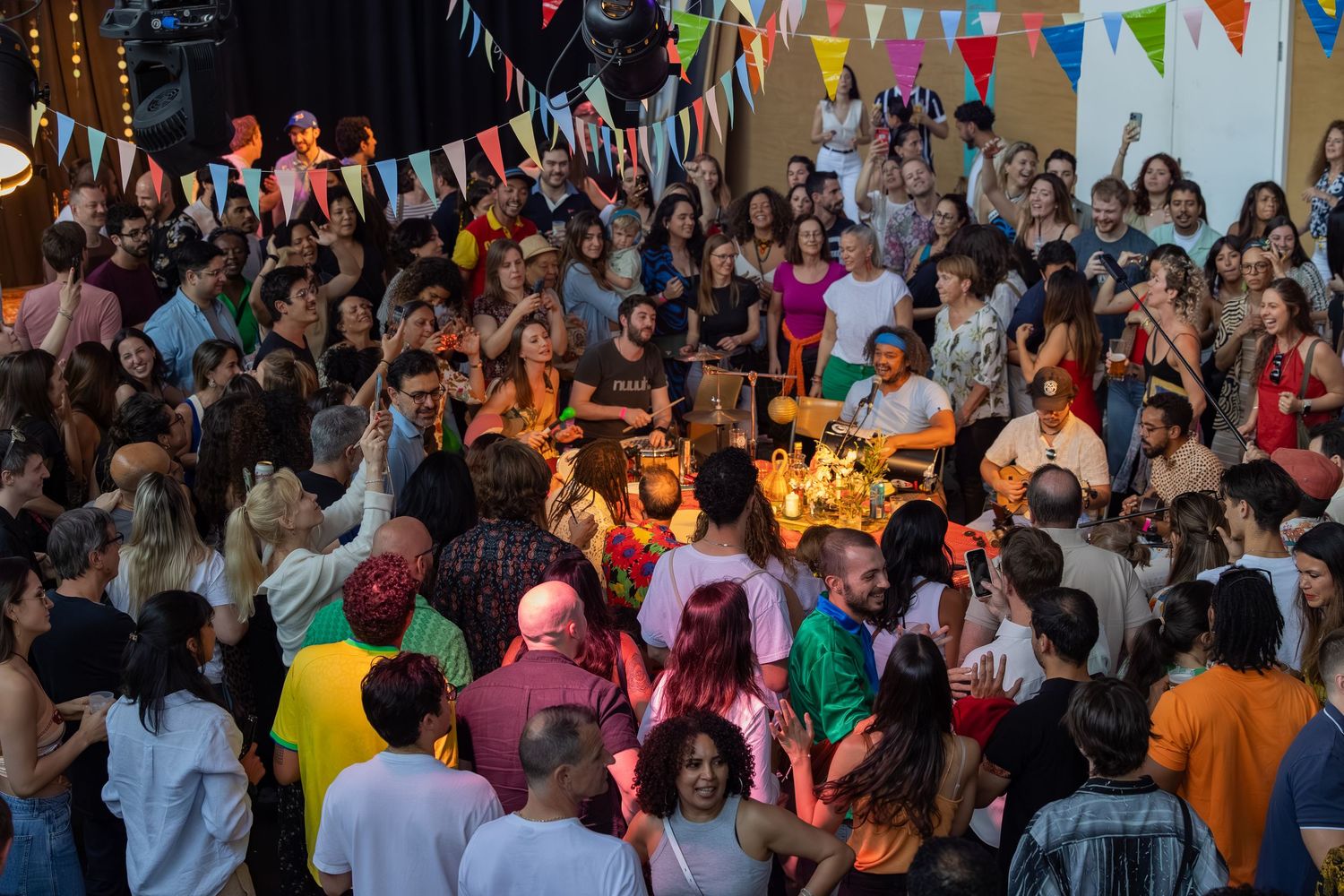 Large crowd dancing and celebrating at indoor festival with colorful decorations.