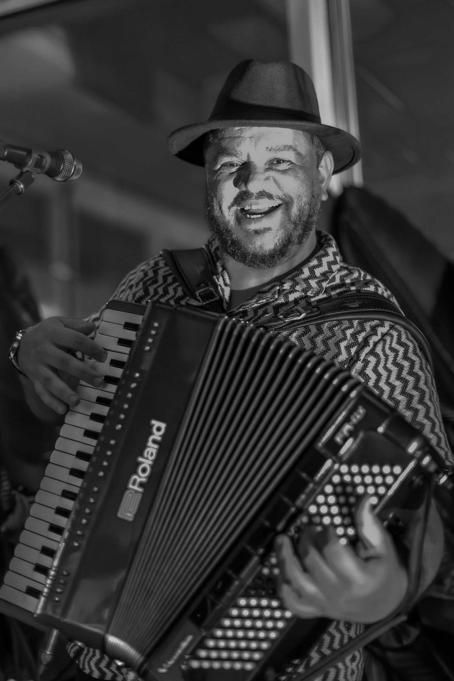 Black and white portrait of accordion player wearing fedora performing with joy.