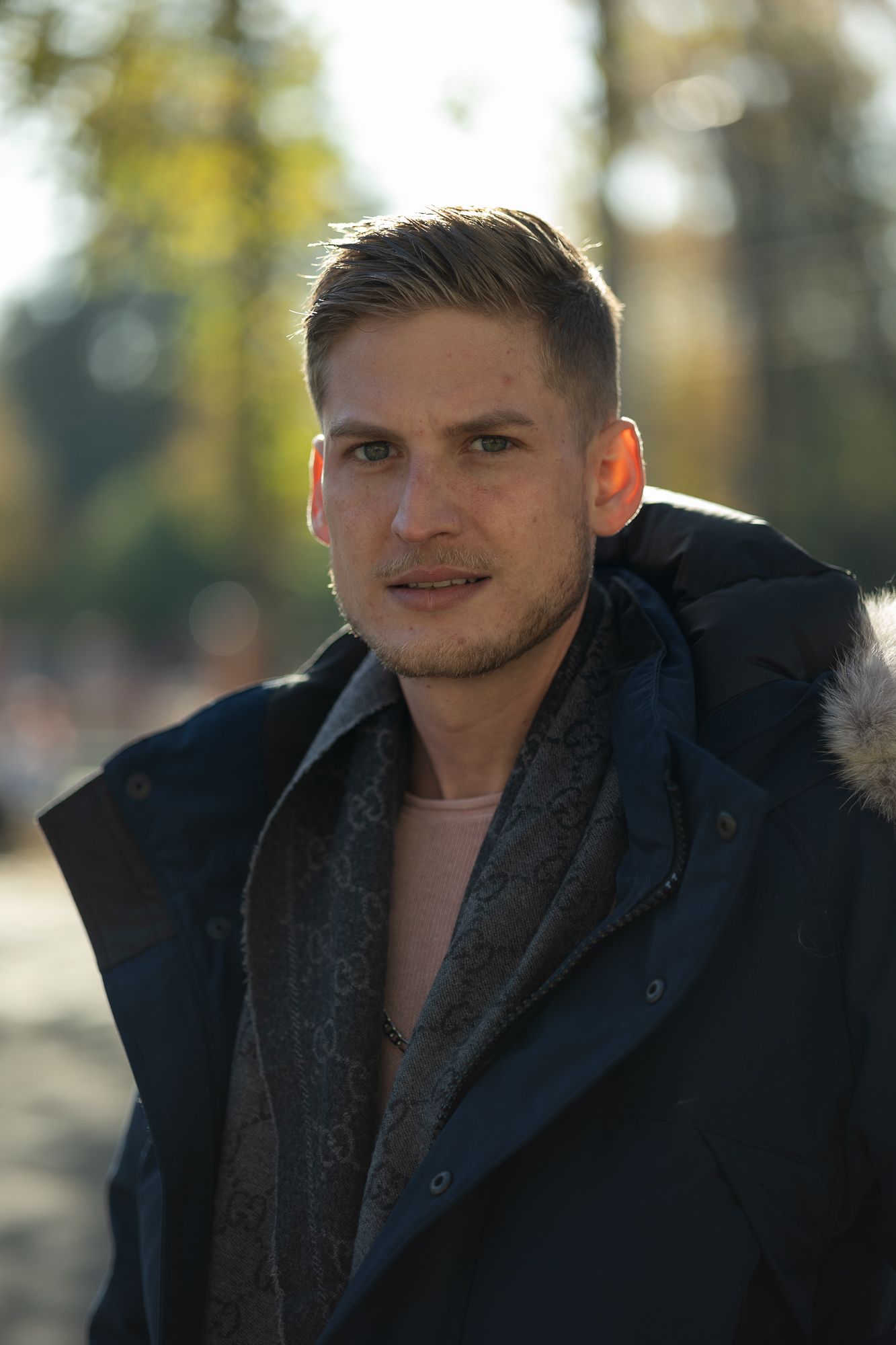 Outdoor portrait wearing a navy winter coat with fur trim hood captured in warm sunlight.