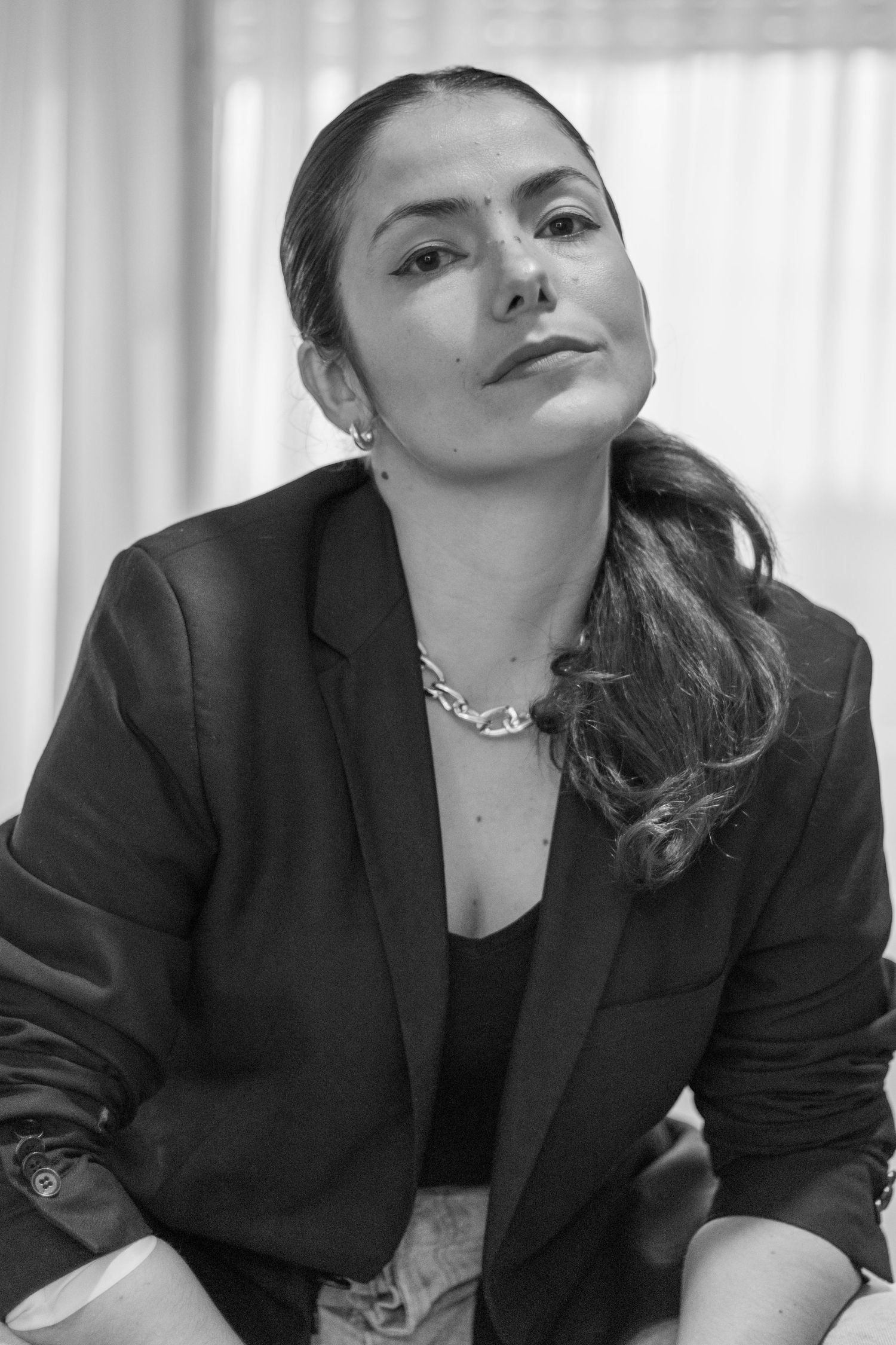 Professional in black blazer and necklace in monochrome portrait setting.