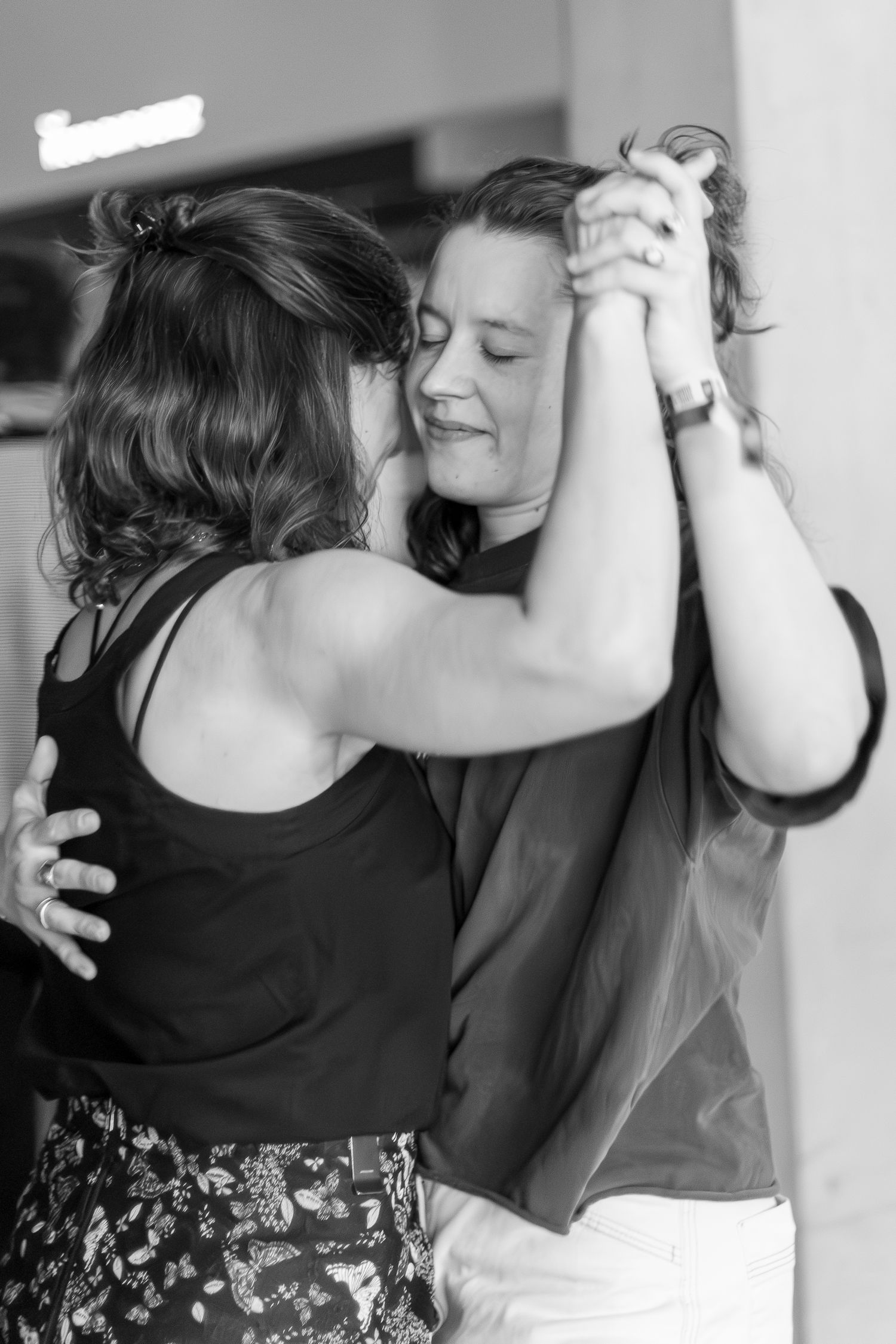 Two dancers embrace in an intimate dance pose captured in black and white.