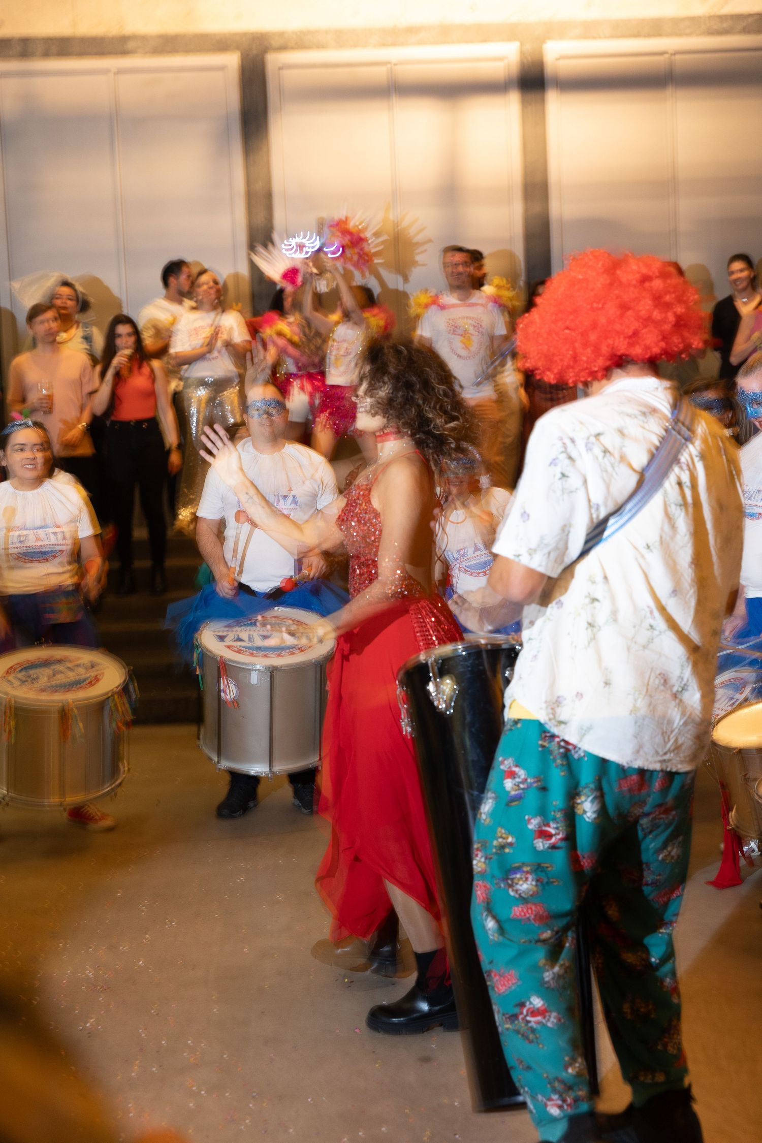 Musicians and dancers perform in a warehouse space with festive costumes and drums.