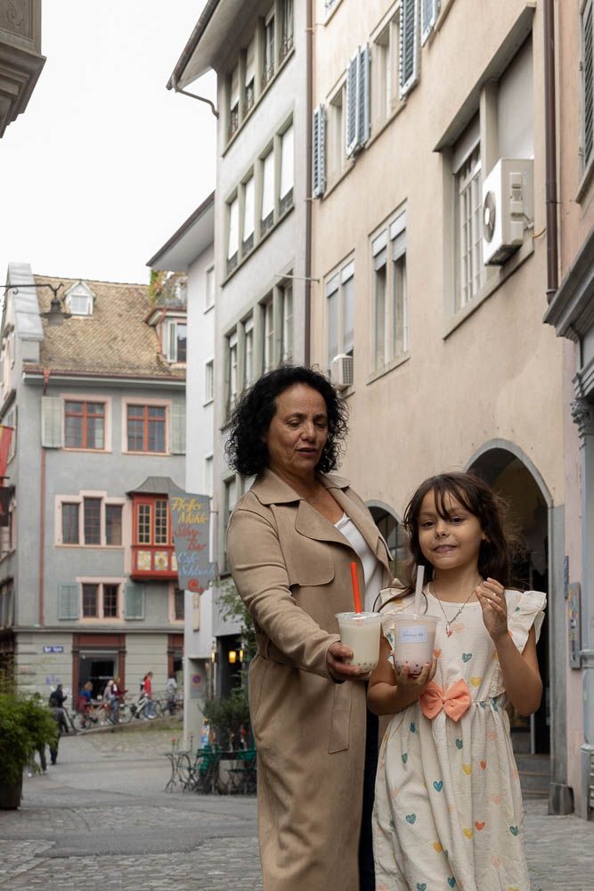 People enjoying beverages while walking through charming European old town streets.