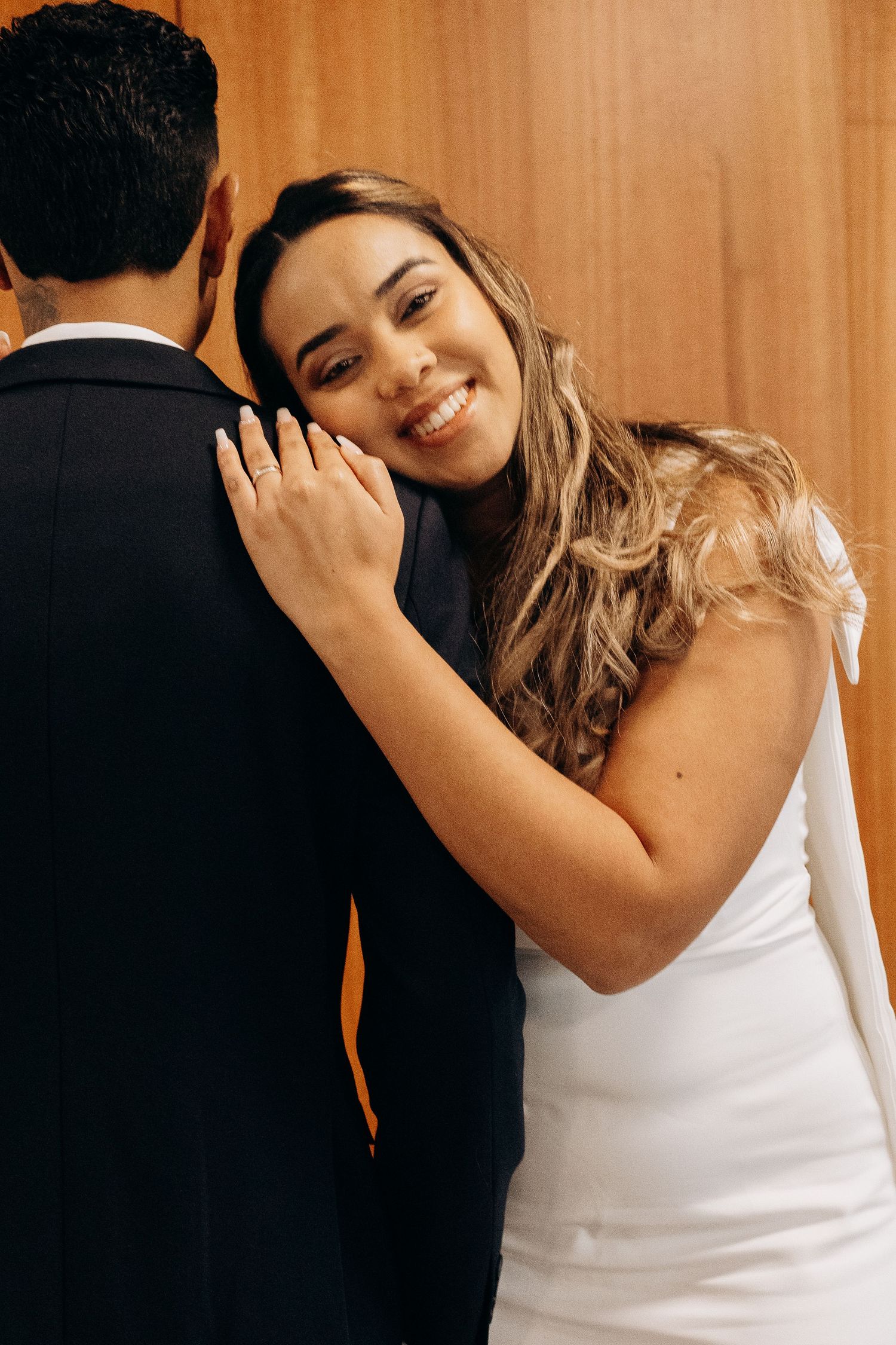 Intimate wedding moment captured against wooden wall background.