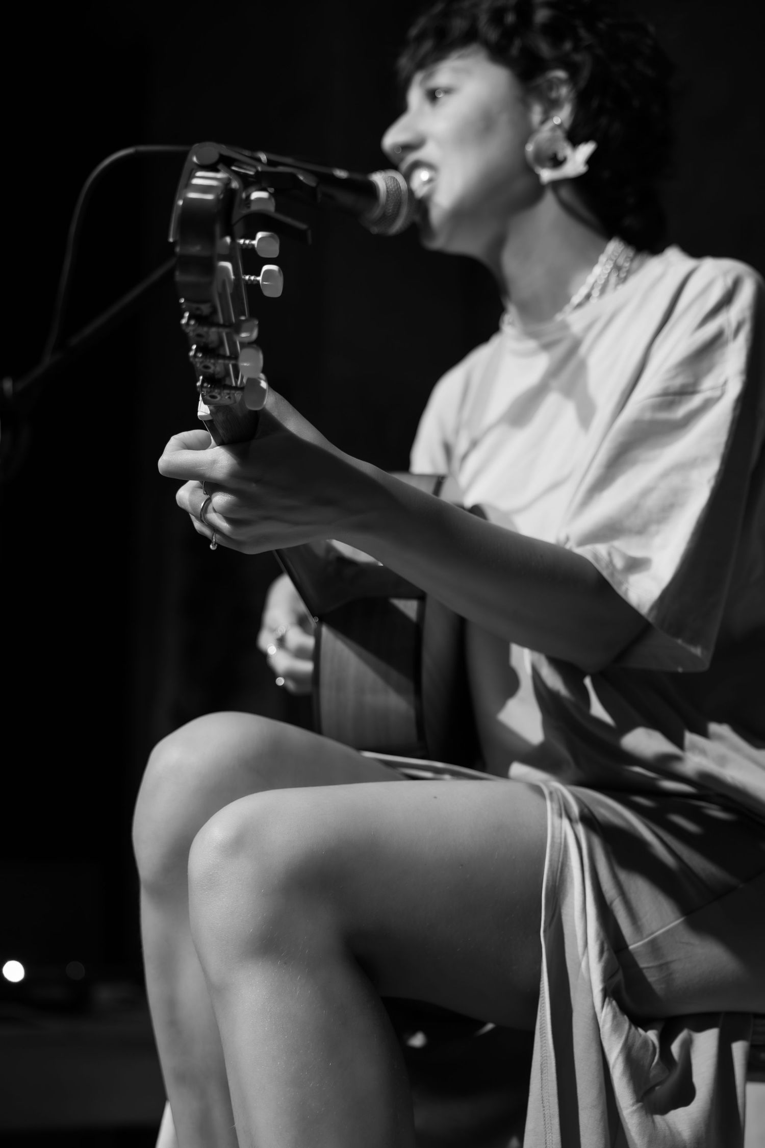 Black and white photo of musician performing with acoustic guitar on stage.