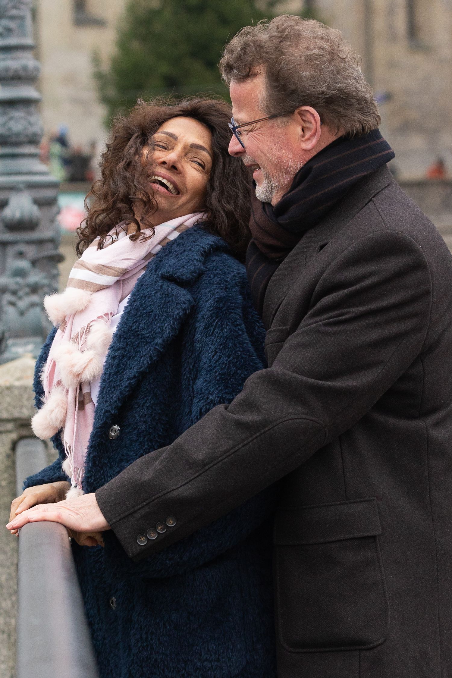 A happy couple sharing a lighthearted moment together against an urban backdrop.