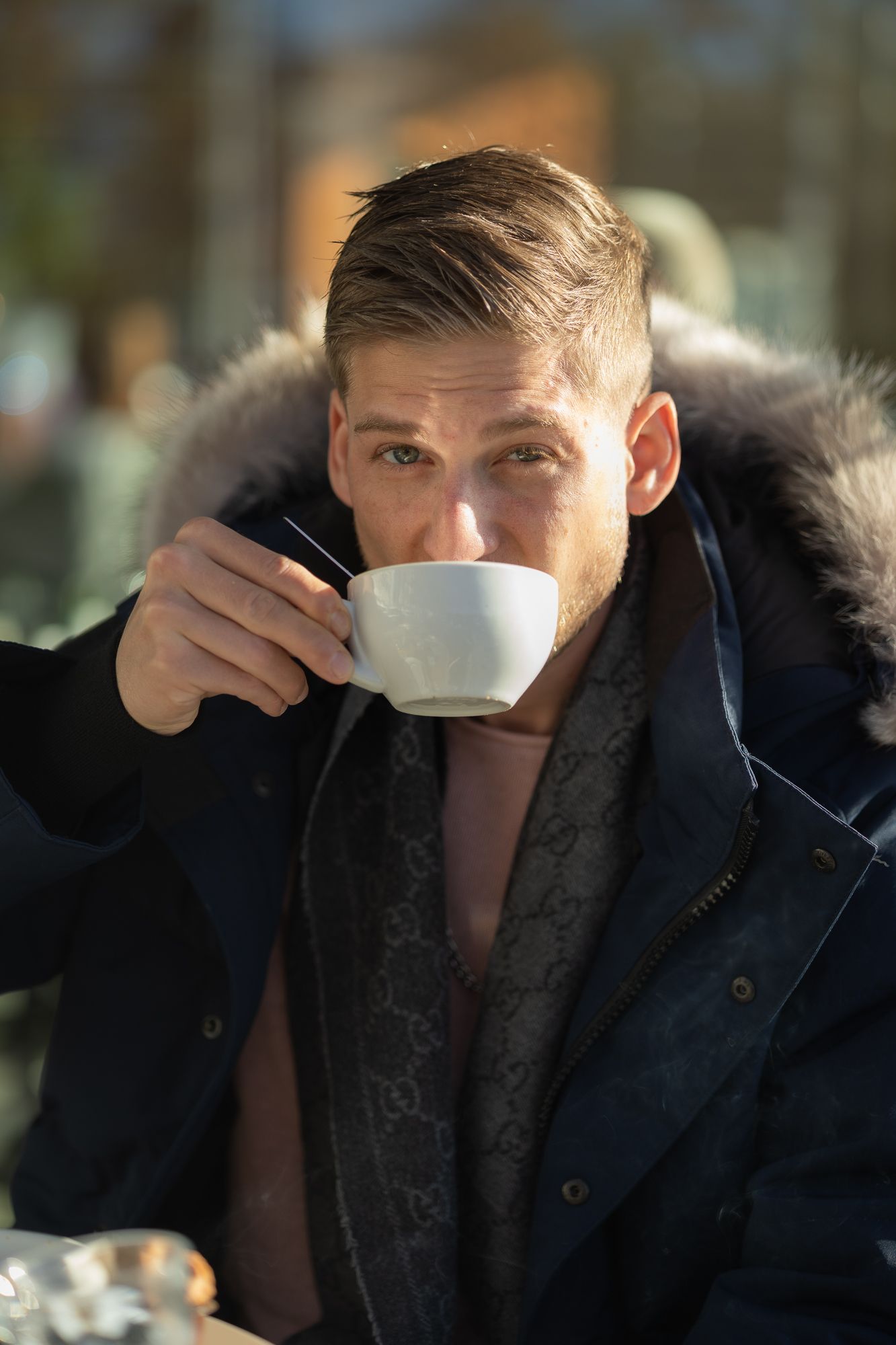 Lifestyle photo of someone enjoying coffee while wearing a winter coat outdoors.