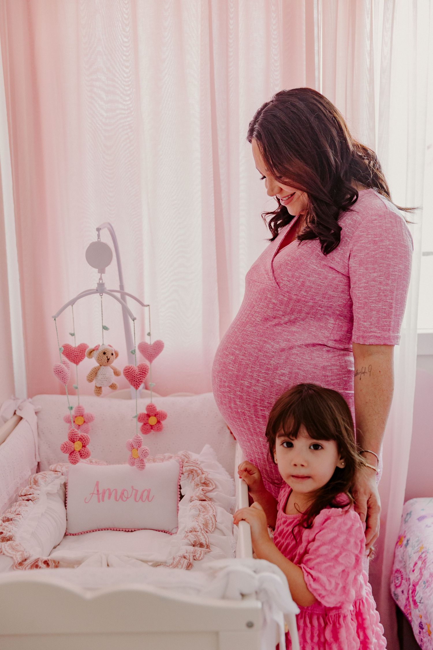 A nursery scene with pink decor and a mother-daughter moment.