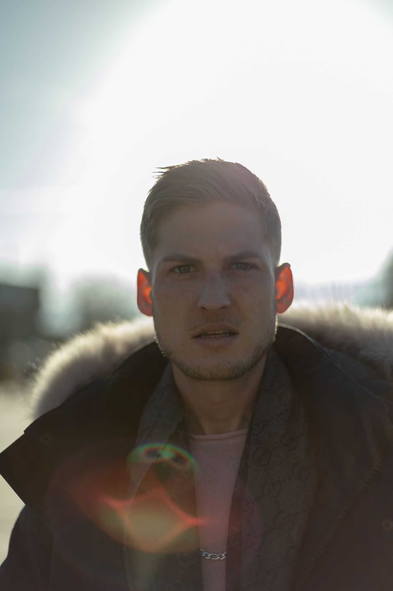 Portrait of person in winter coat with sunlit lens flare effect.