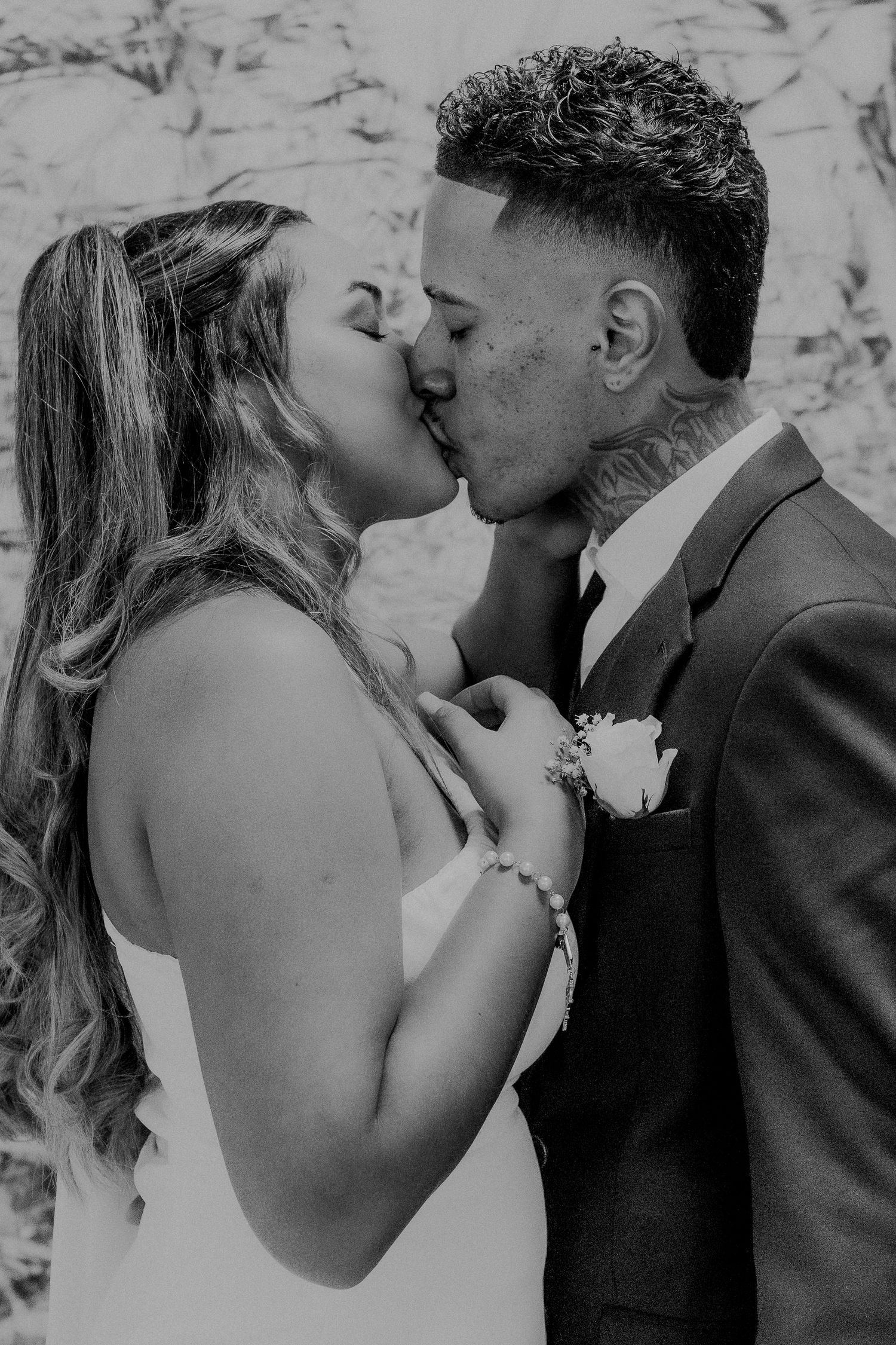 Black and white portrait of newlyweds sharing intimate kiss.