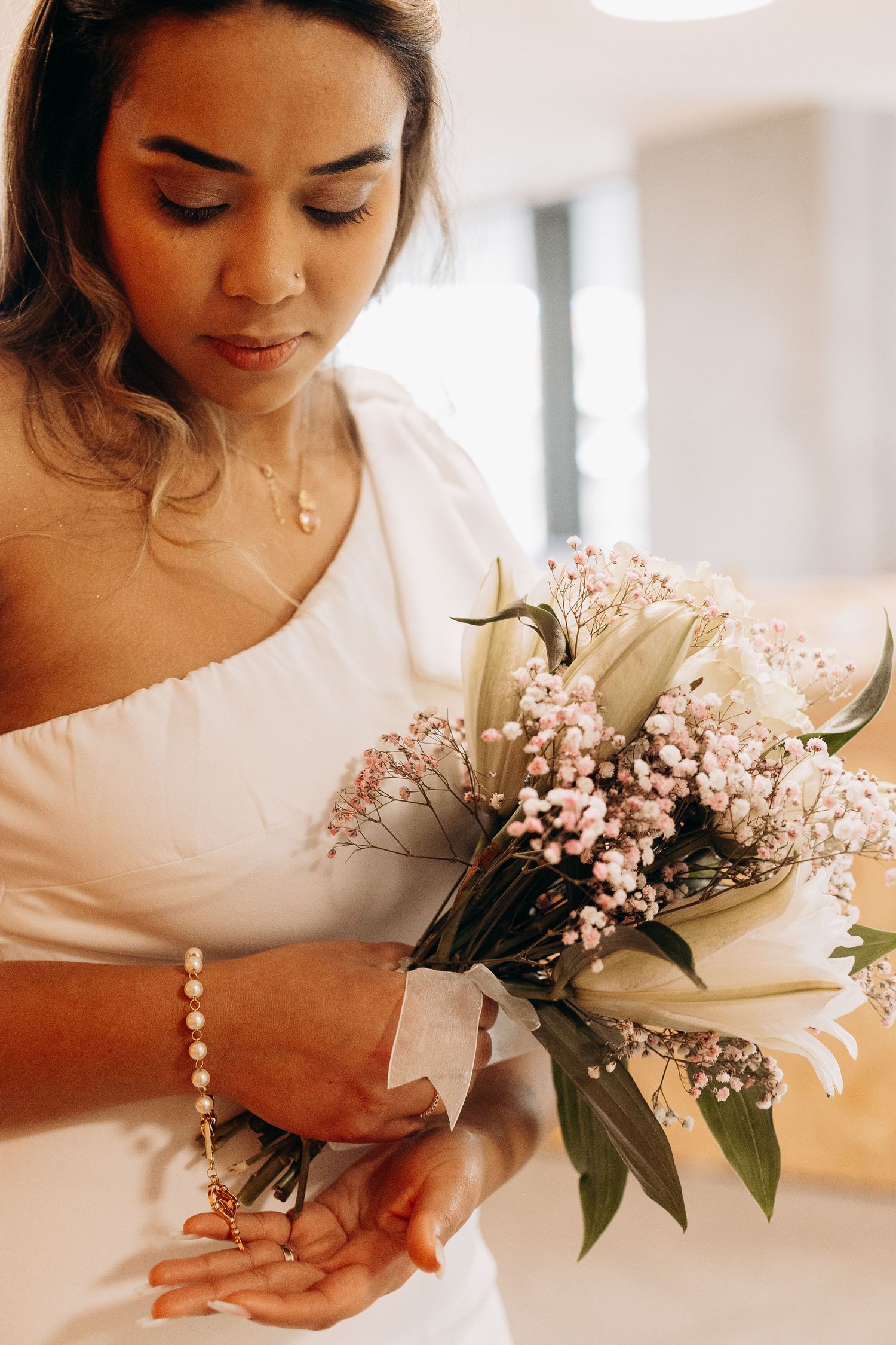 Close-up of bride holding delicate bouquet of white roses and baby's breath.