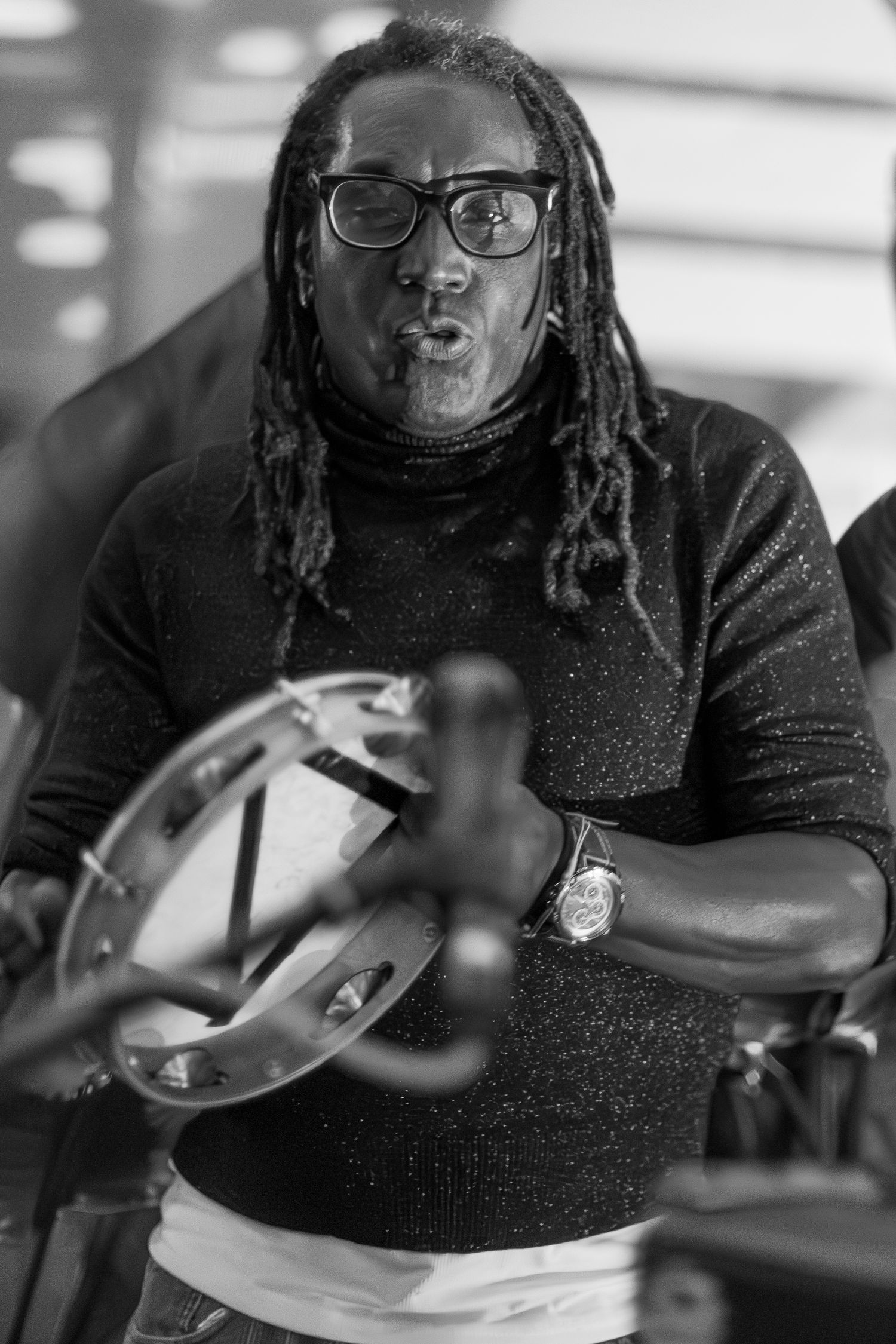 Black and white portrait of musician playing tambourine with passionate expression.