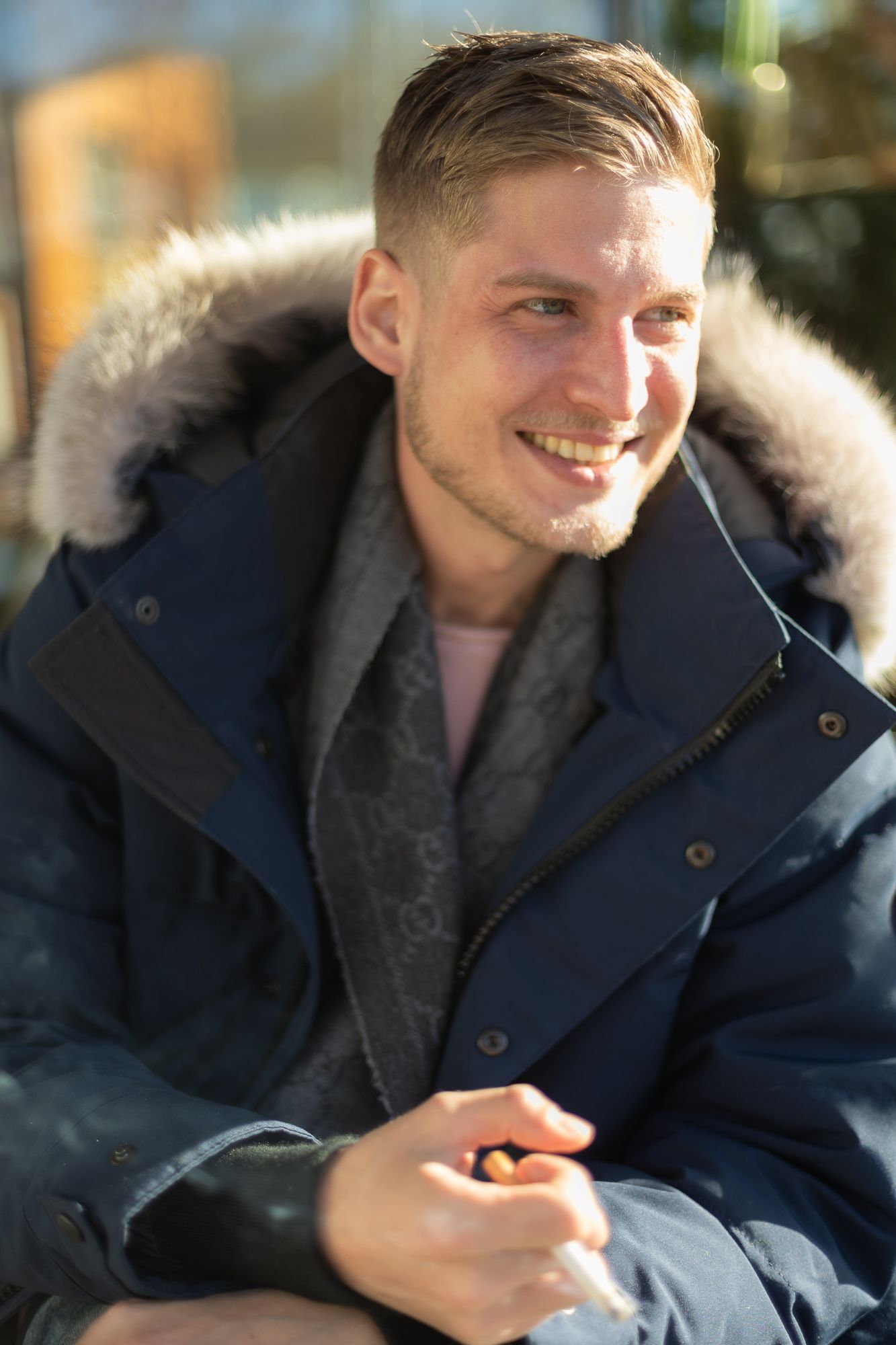 Relaxed winter fashion portrait featuring a fur-trimmed navy parka in natural light.