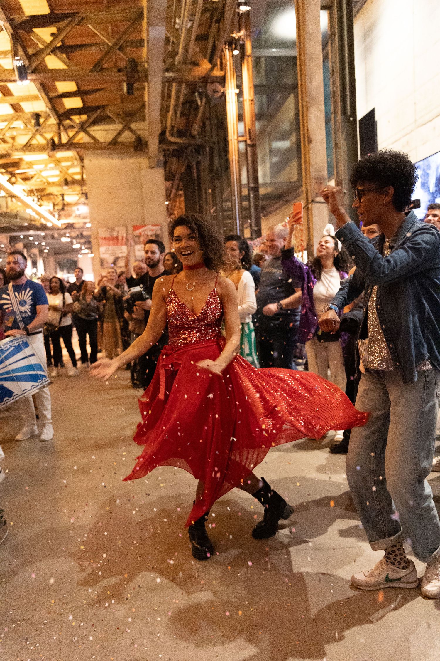 A dancer in a flowing red dress spins during a lively indoor performance.