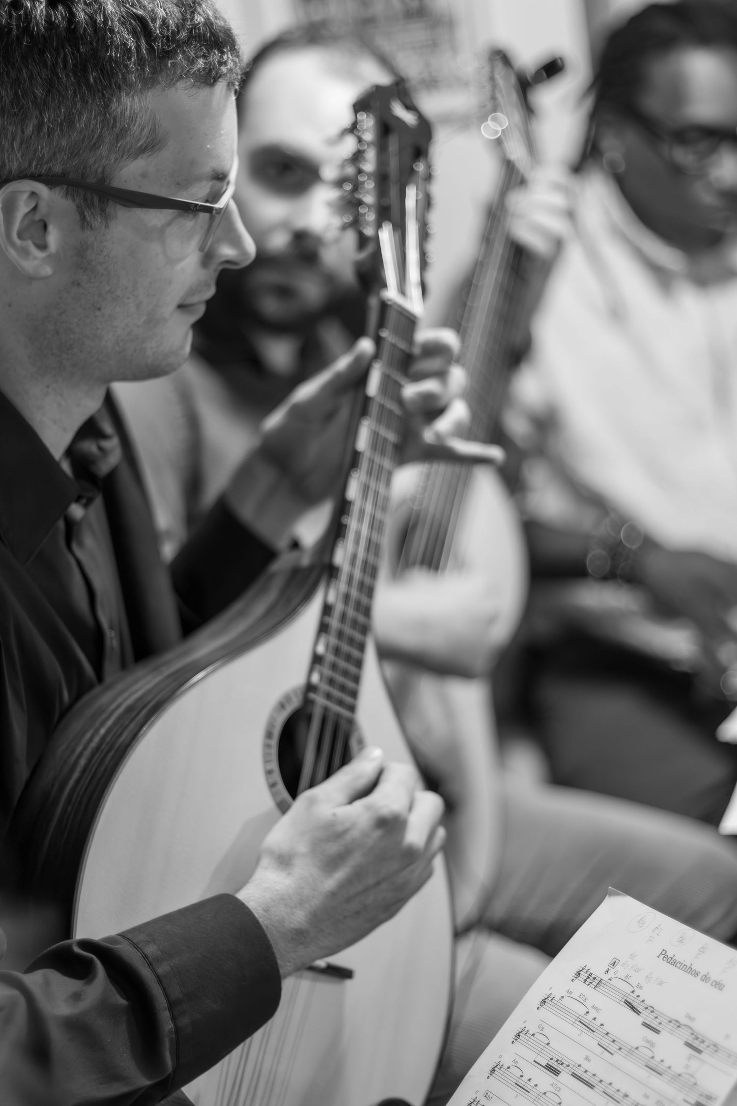 A musician plays an acoustic instrument while reading sheet music during a performance.
