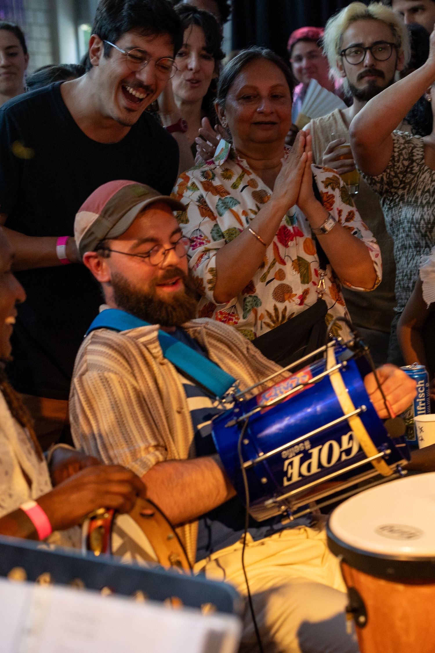Musicians performing with drums at lively indoor celebration with enthusiastic audience.