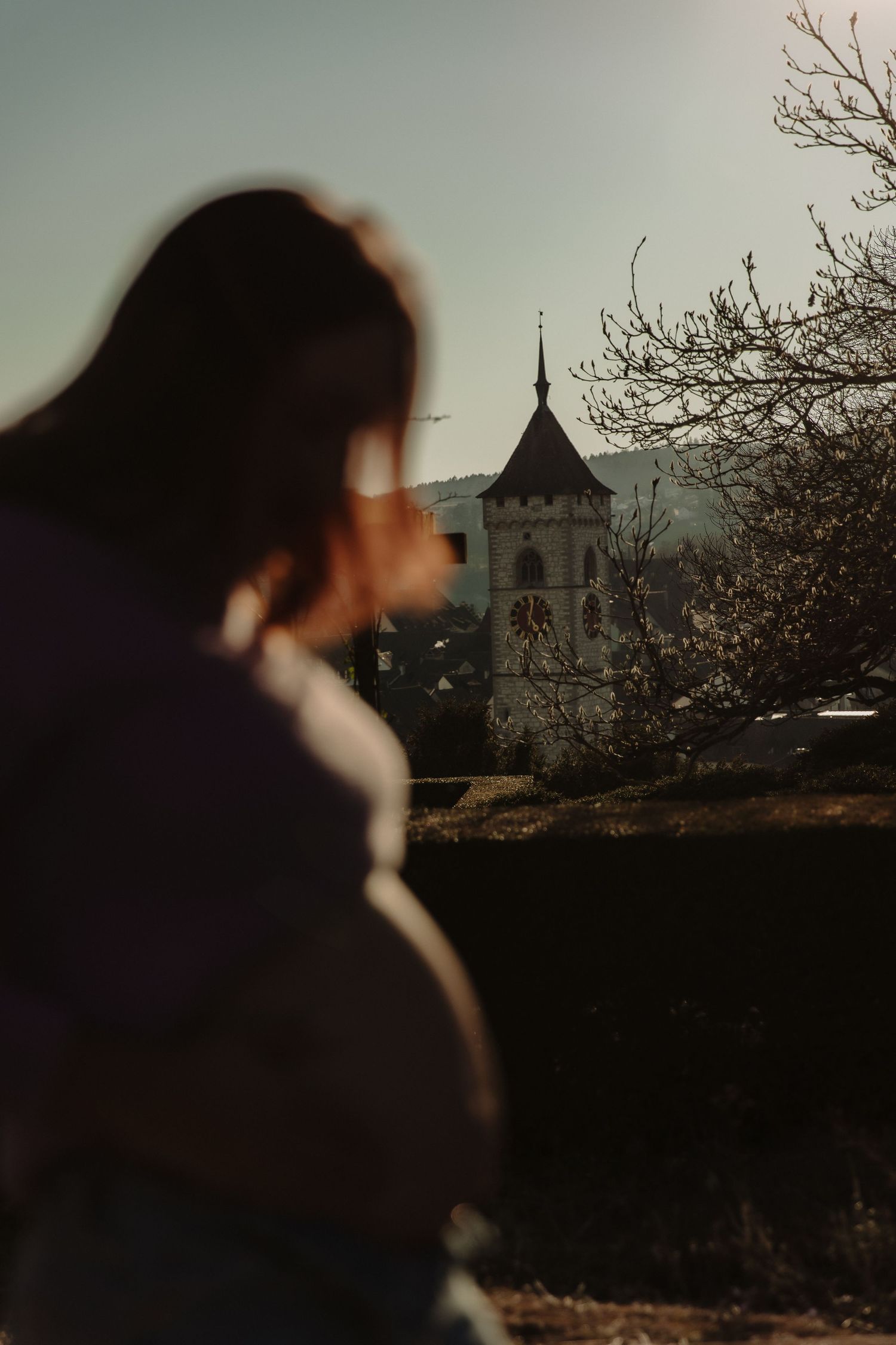 Silhouette of person looking at historic tower during sunset.