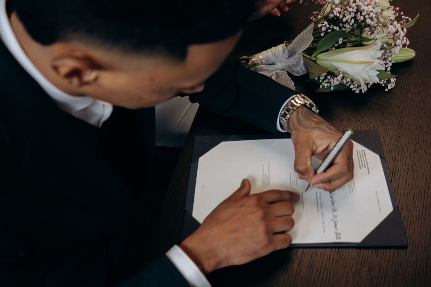 Close-up of hands signing marriage documents at a civil ceremony.