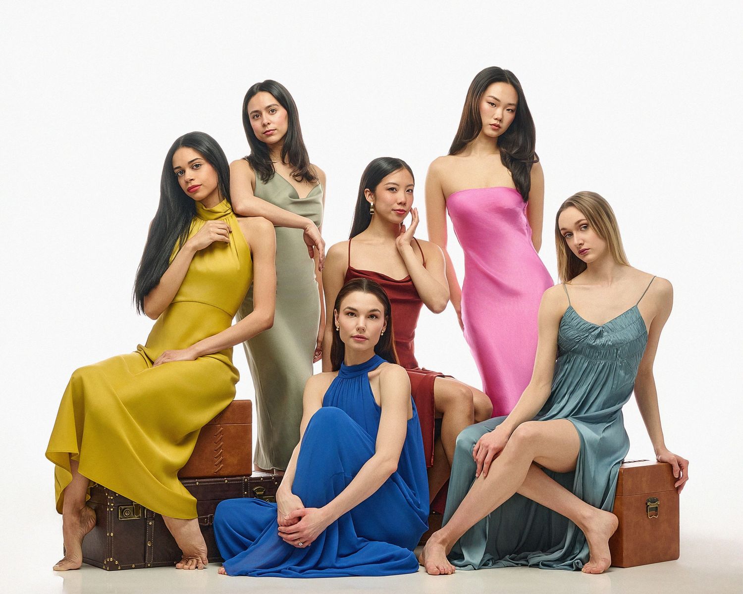 Models in jewel-toned dresses arranged in artistic composition.
