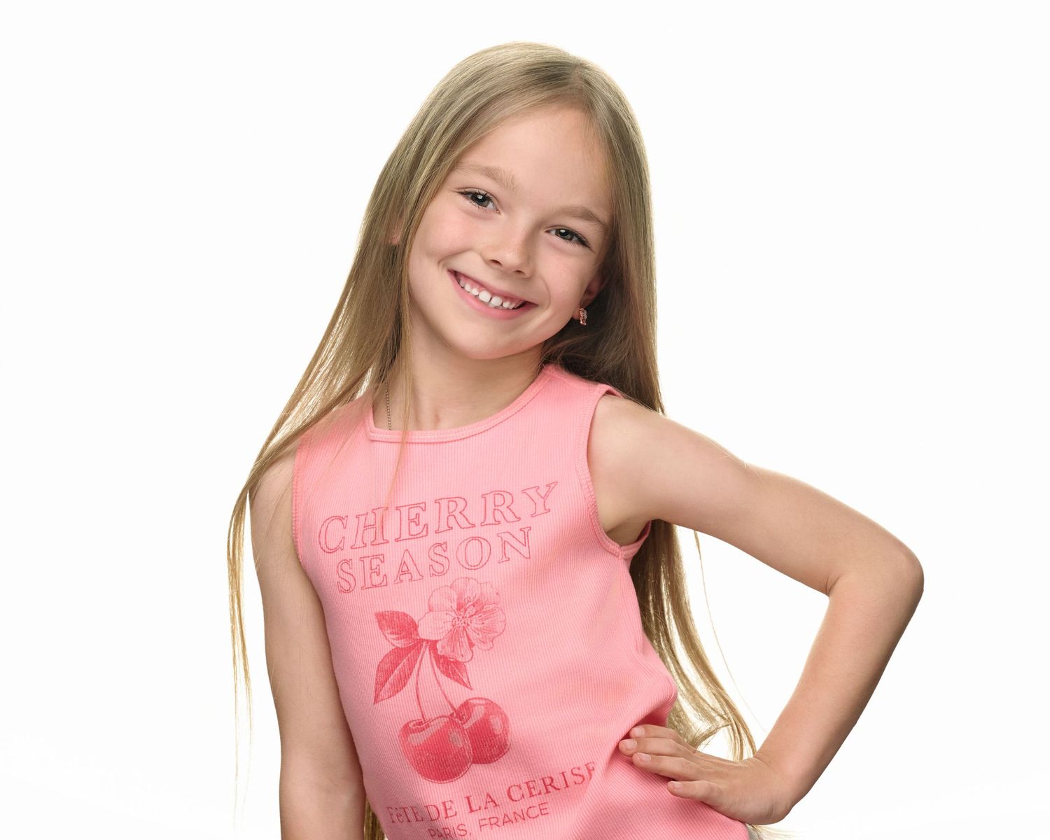 Young person in pink cherry-themed tank top smiling against white background.
