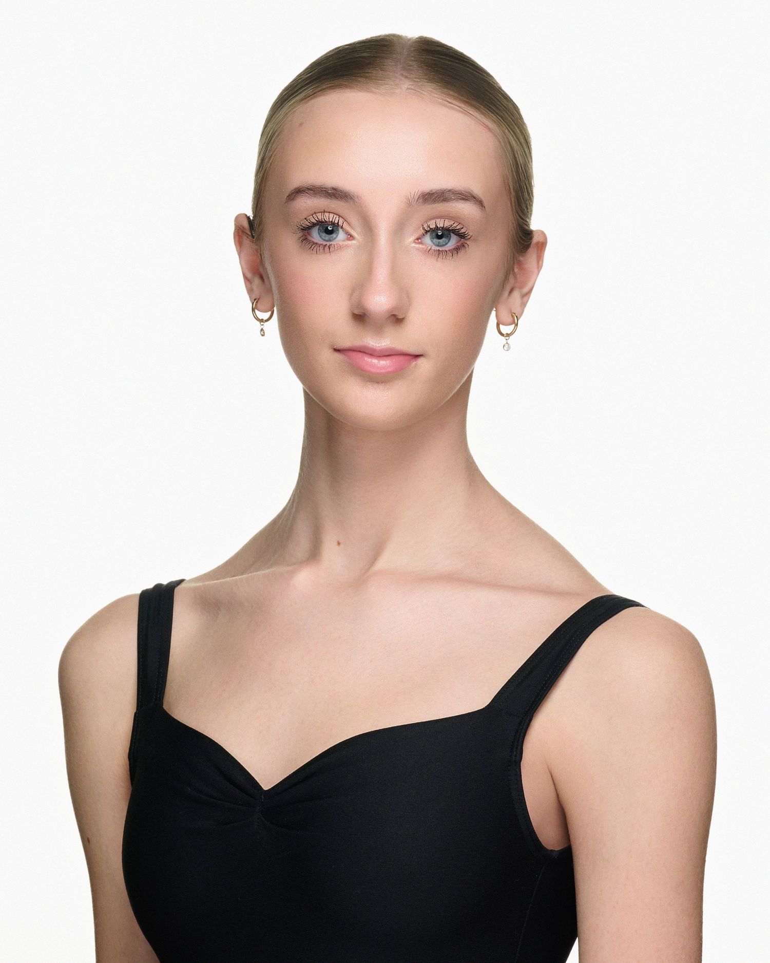 Portrait of a ballet dancer wearing a black leotard against a white background.