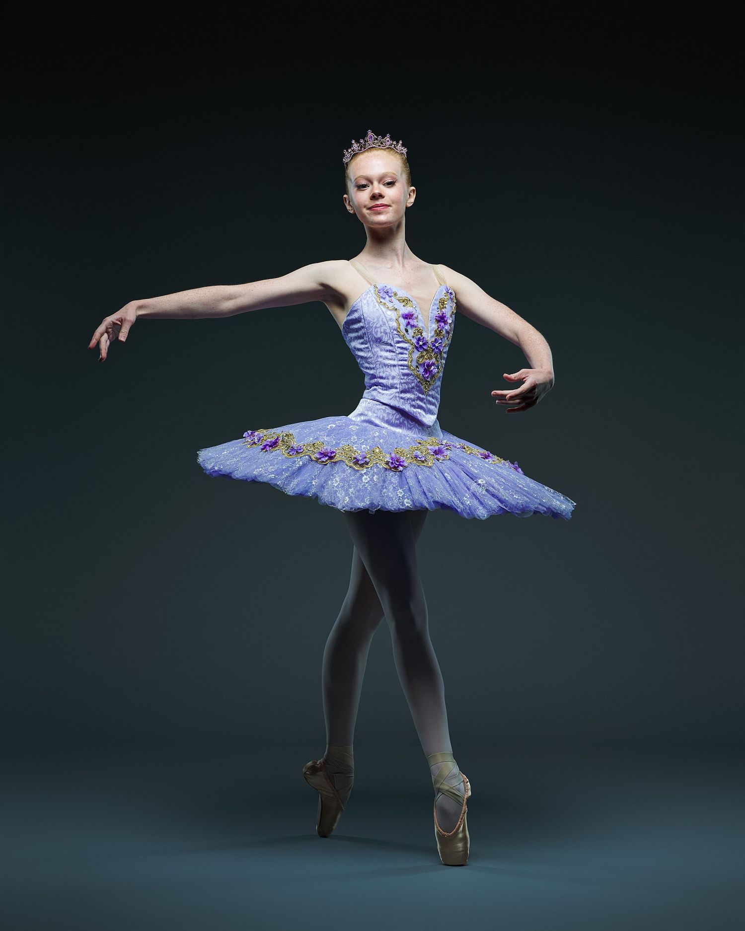 Ballerina poses gracefully in lavender classical tutu with delicate embellishments.