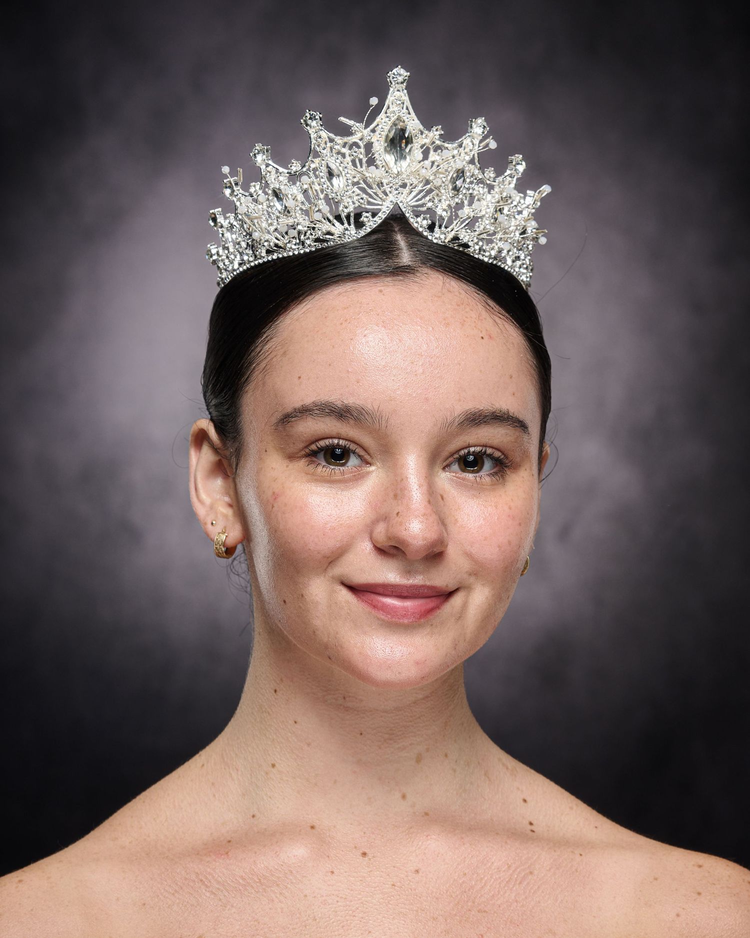 Elegant crystal tiara crowns dancer against dramatic dark background.