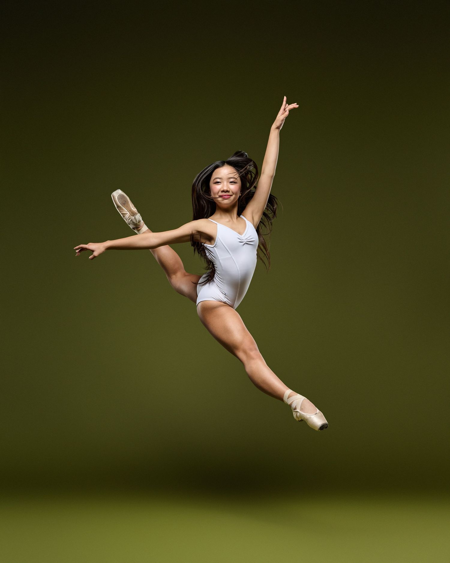 A graceful ballet dancer performs multiple mid-air jumps and poses in an artistic sequence against a dark backdrop.