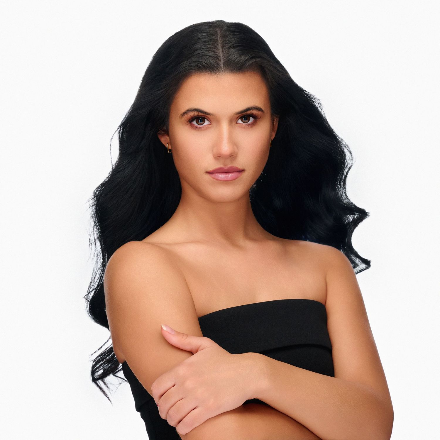 Glamour portrait with flowing black hair and strapless top against white background.