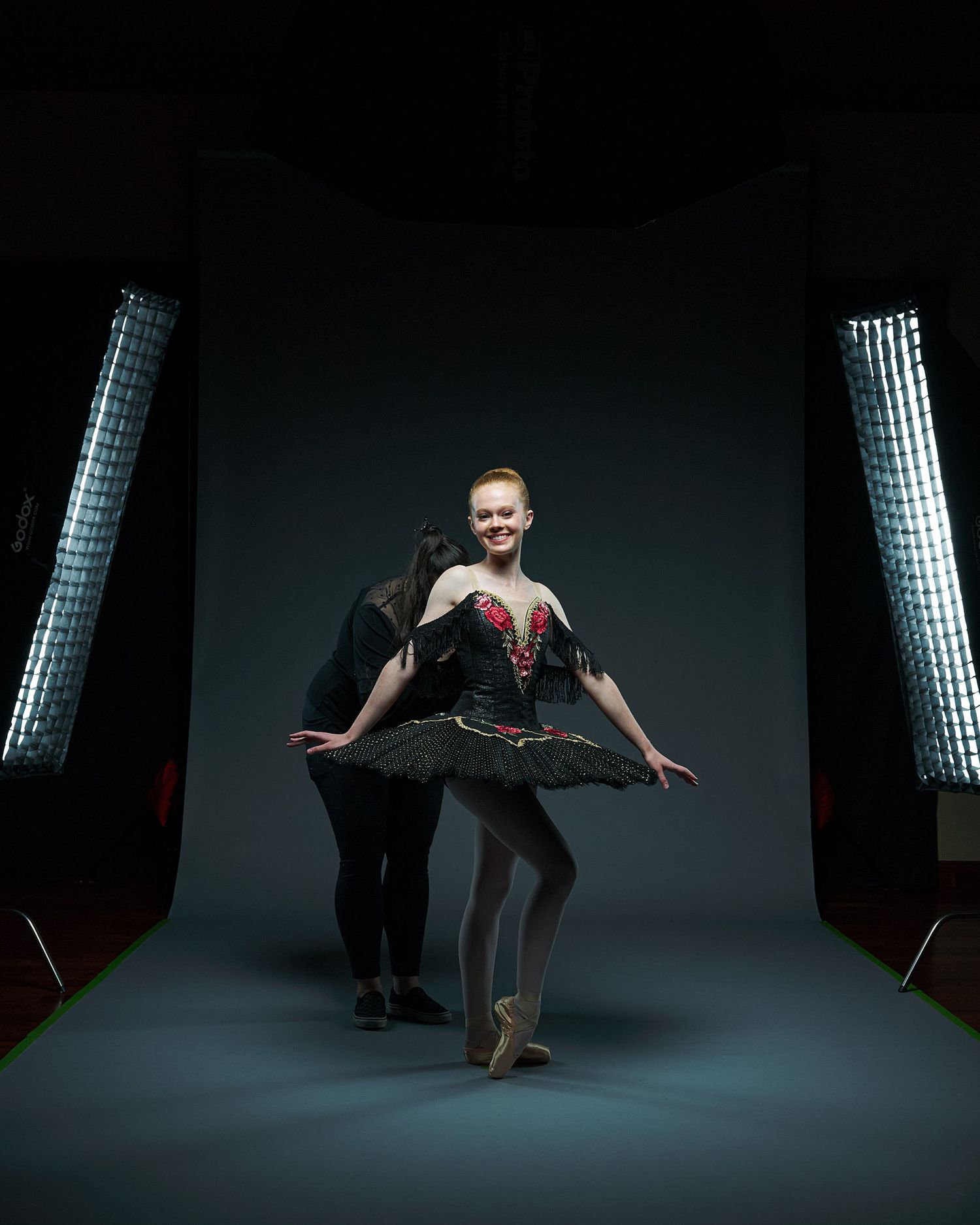 Dancer in black tutu poses in studio with dramatic lighting and softboxes.