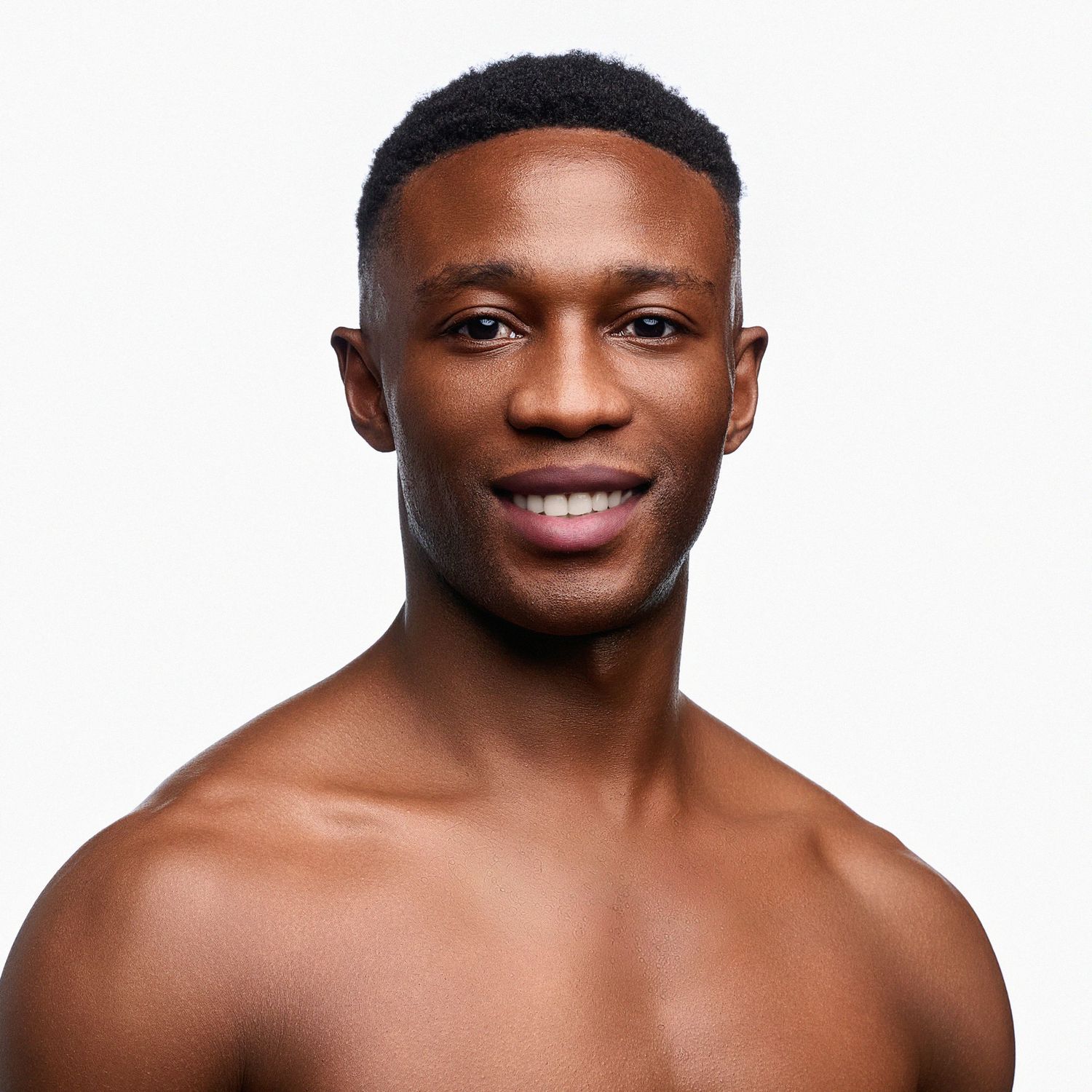 Headshot of a ballet dancer smiling against white background.