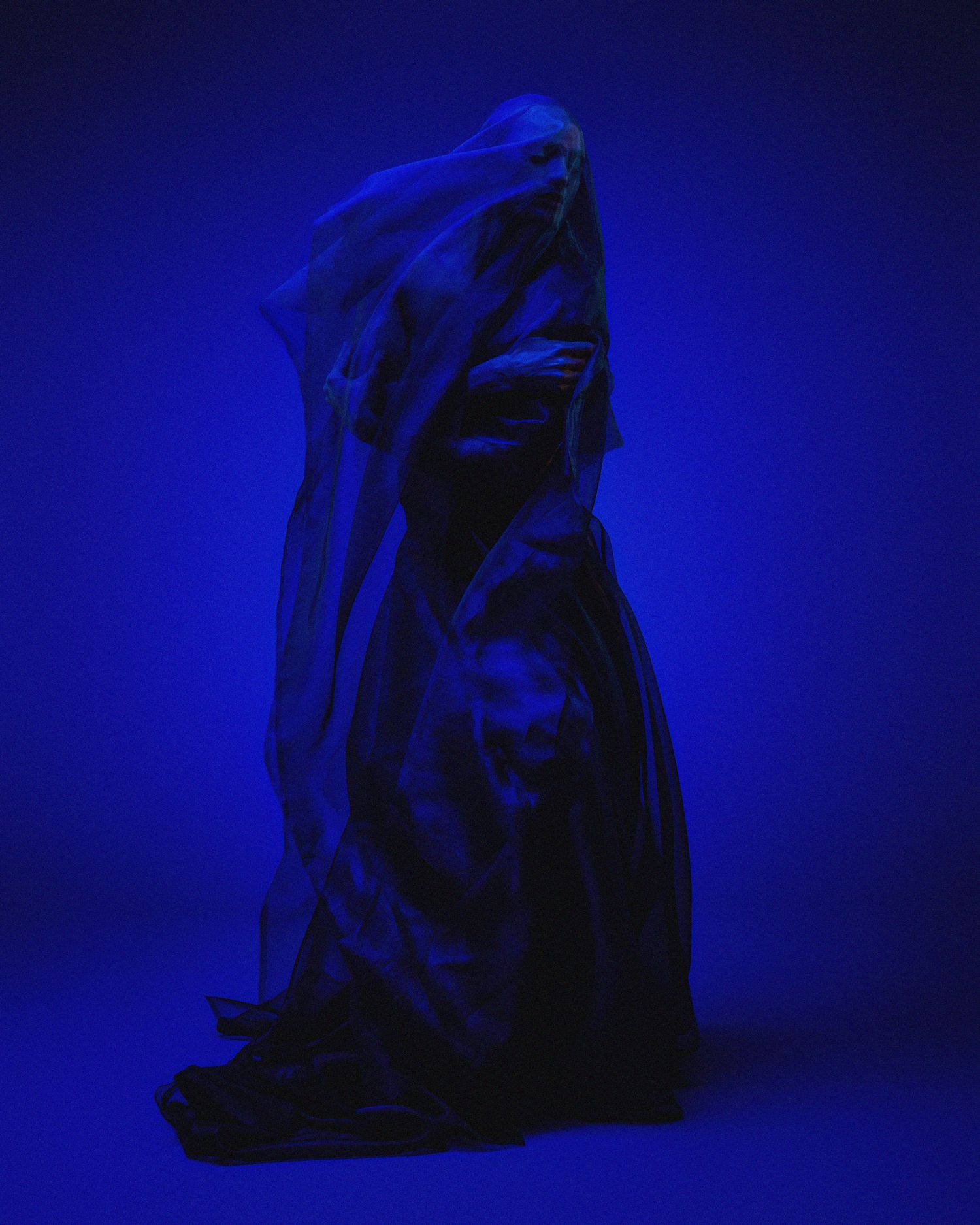 Abstract fabric study in deep blue lighting creating mysterious shapes and shadows.