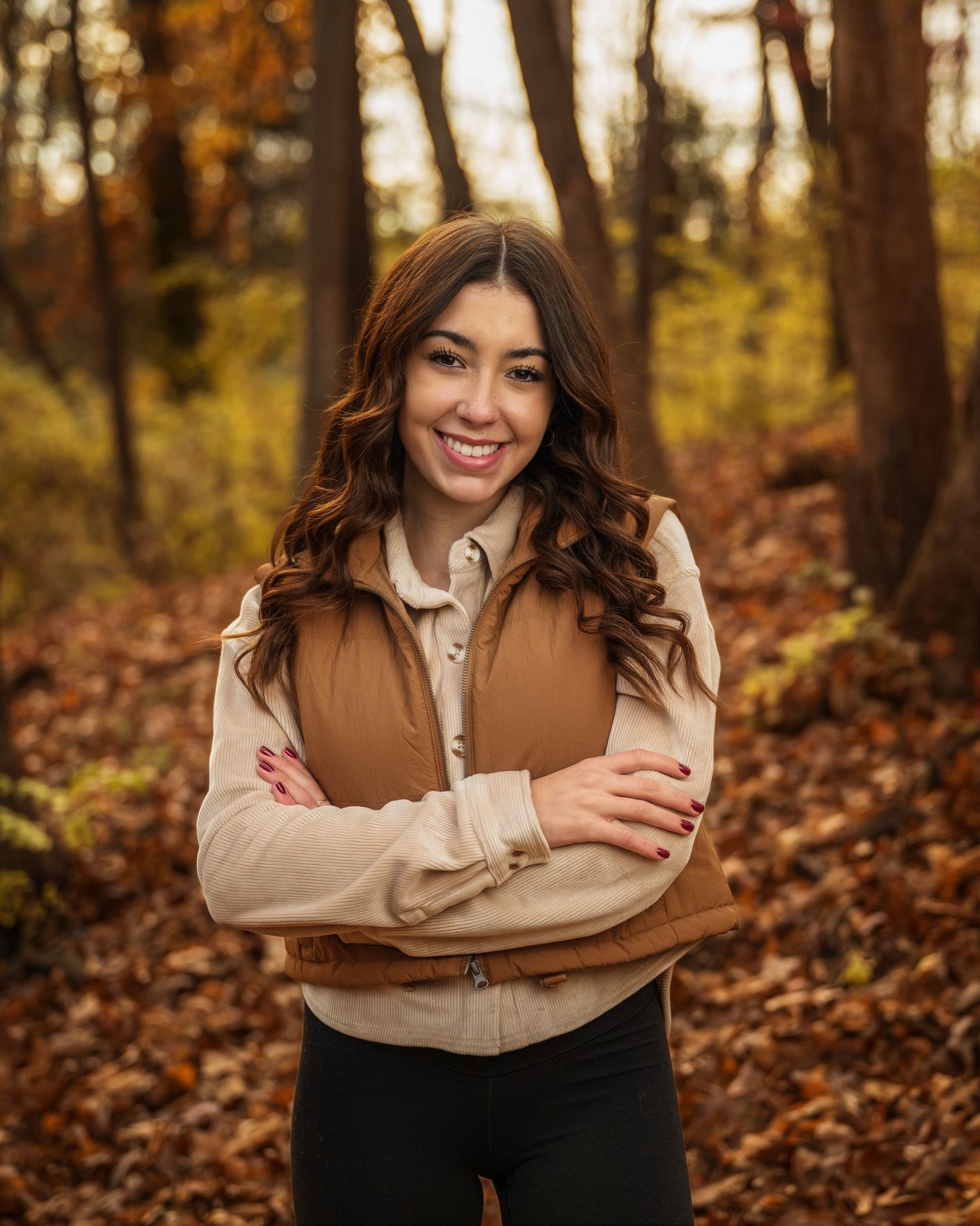 Portrait in autumn forest wearing brown vest and beige jacket.
