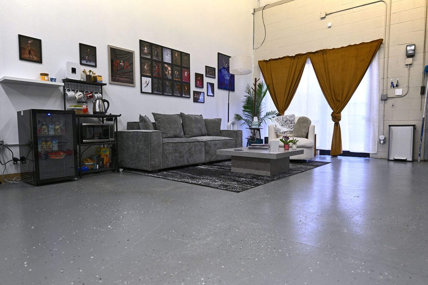 Photography studio waiting area with gray sectional sofa and brown curtains against white walls.