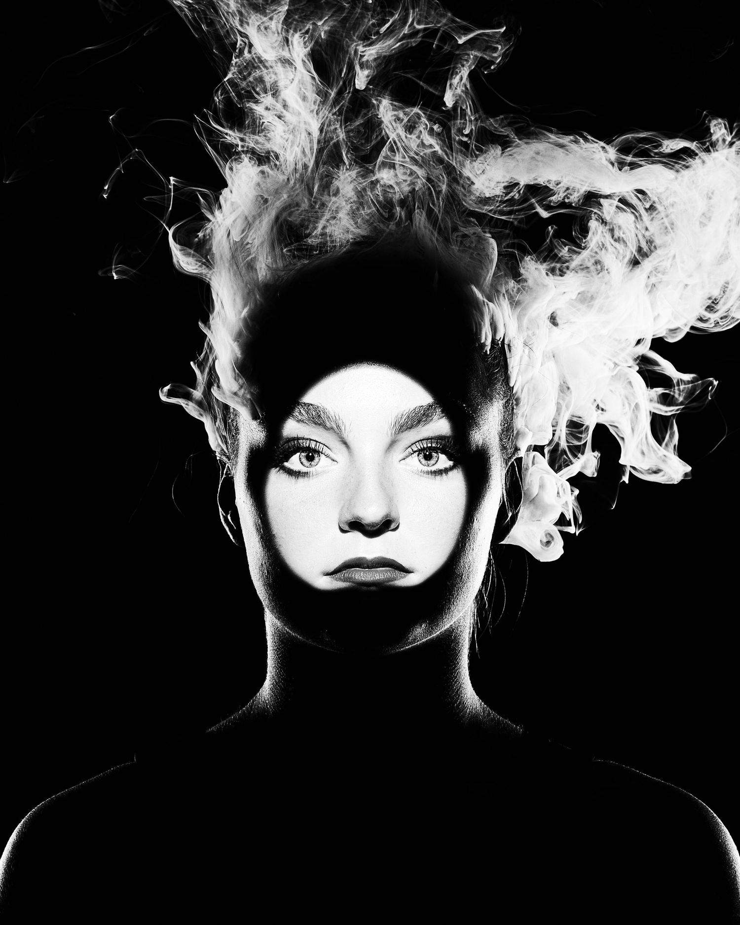 Dramatic black and white portrait with smoke effect creating ethereal atmosphere.