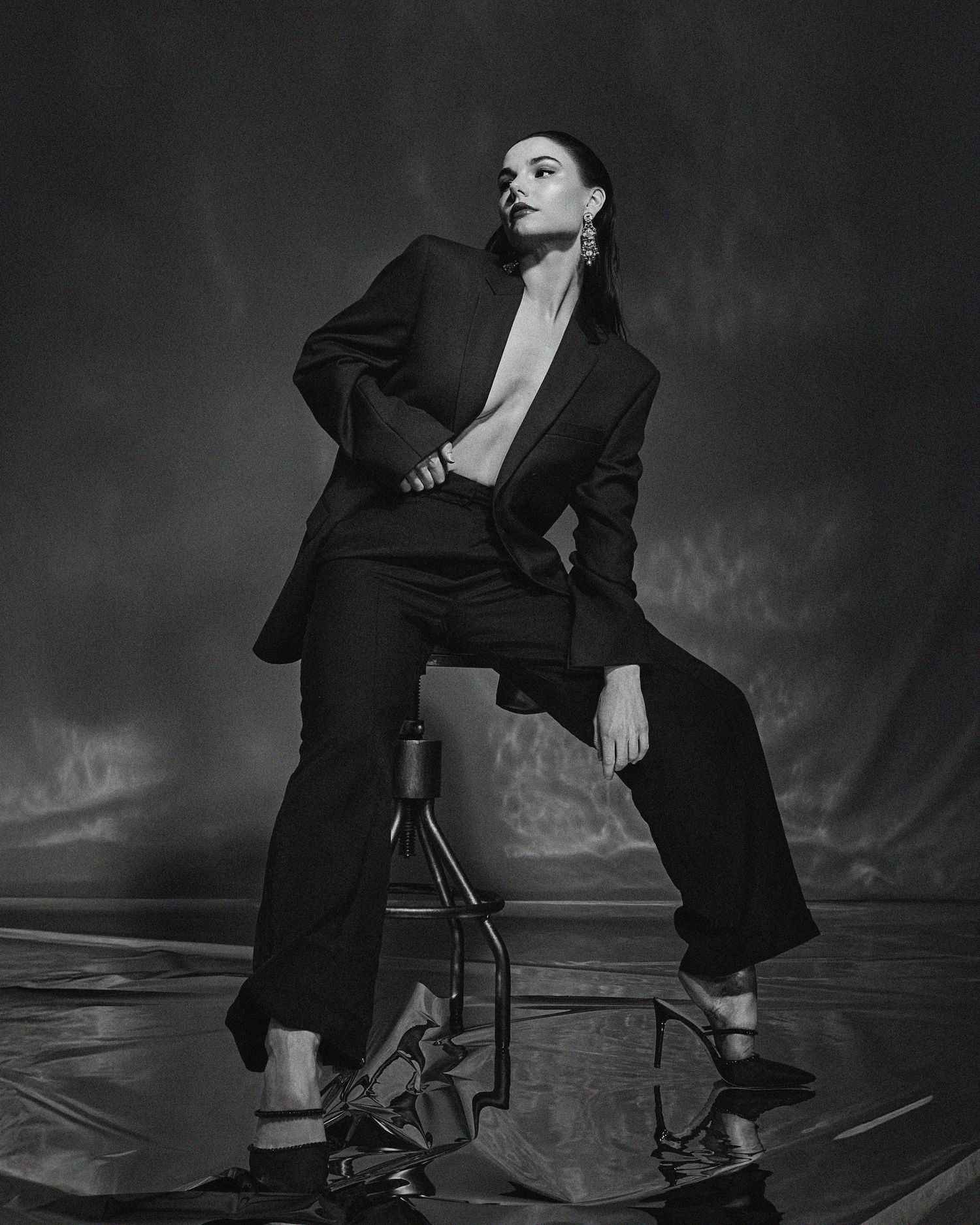Monochromatic fashion portraits featuring person in black suit posing dramatically on chair.