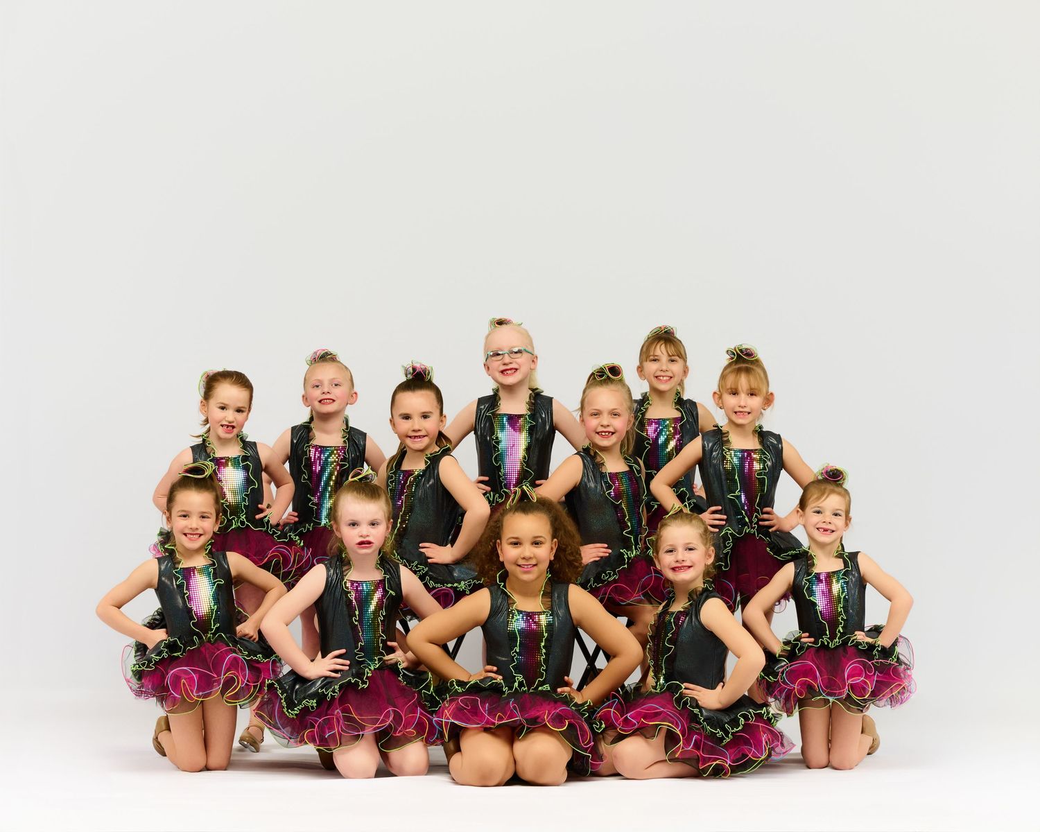 Young dancers in sparkly performance costumes lined up for group photo.