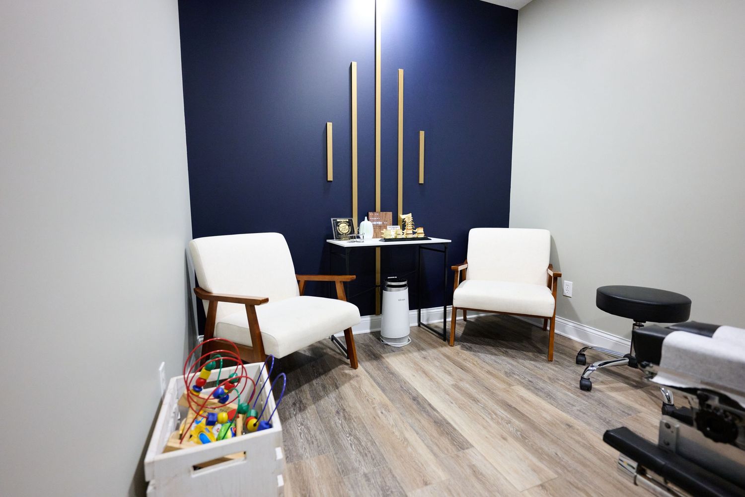 Medical consultation room with navy accent wall, white chairs, and wooden decorative elements.