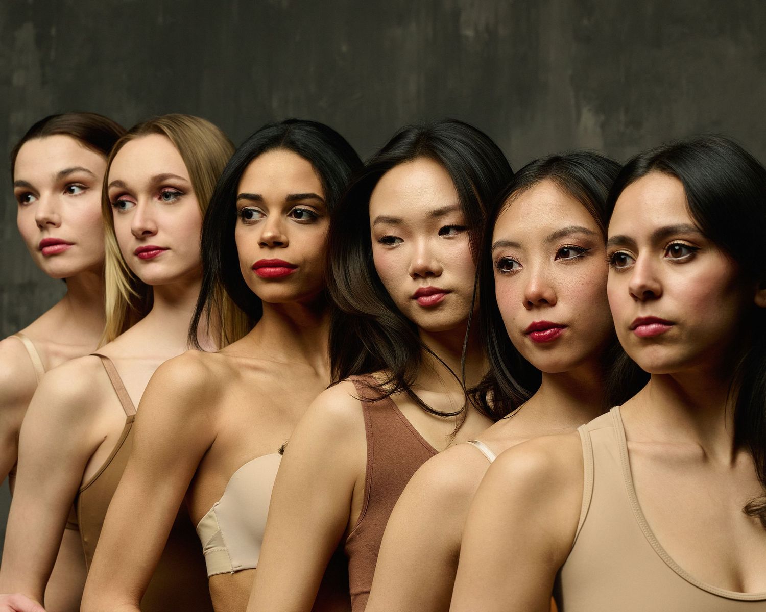 Close-up beauty portrait showing diverse models in neutral tones.