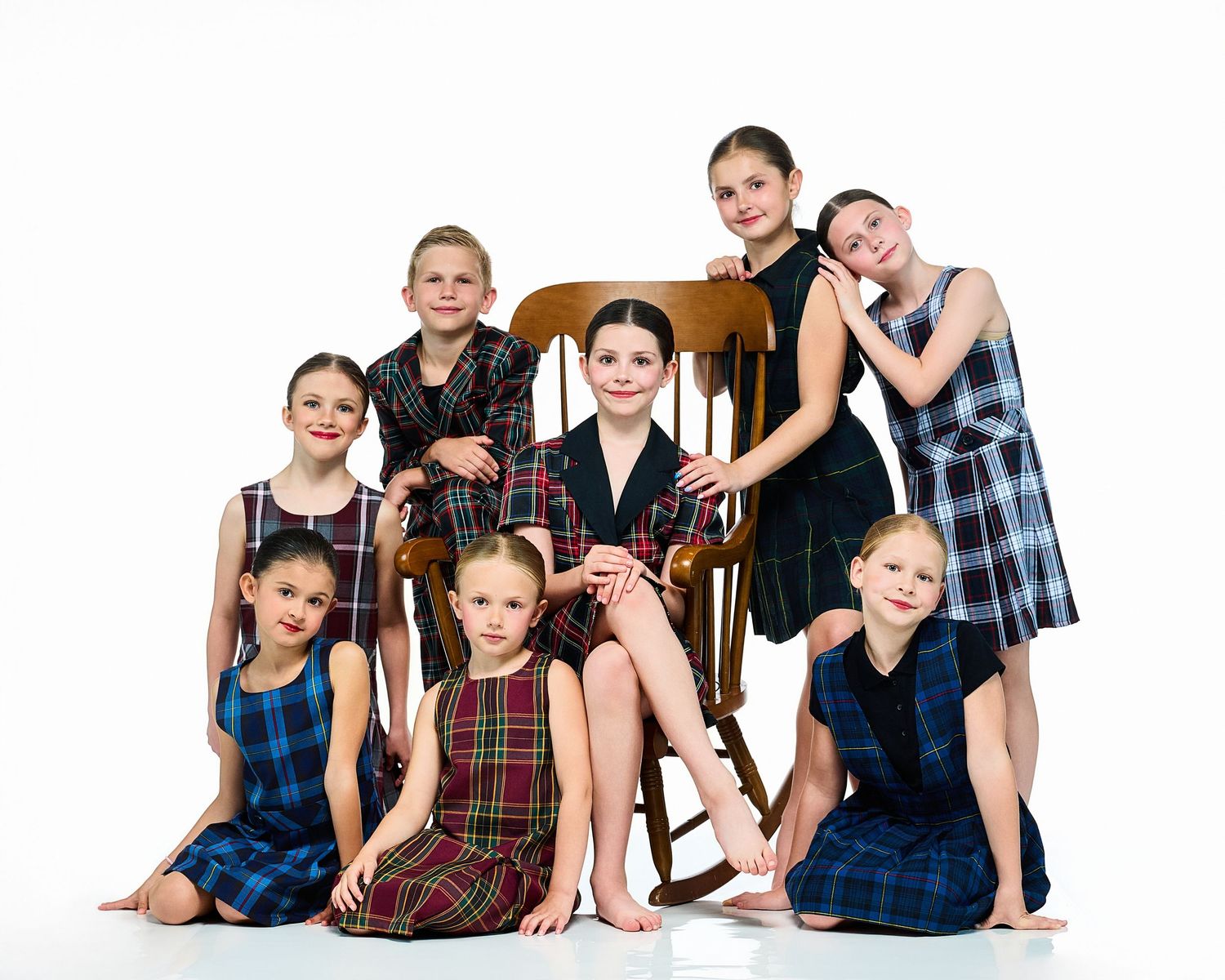 Group portrait of children in casual clothing sitting together on white background.
