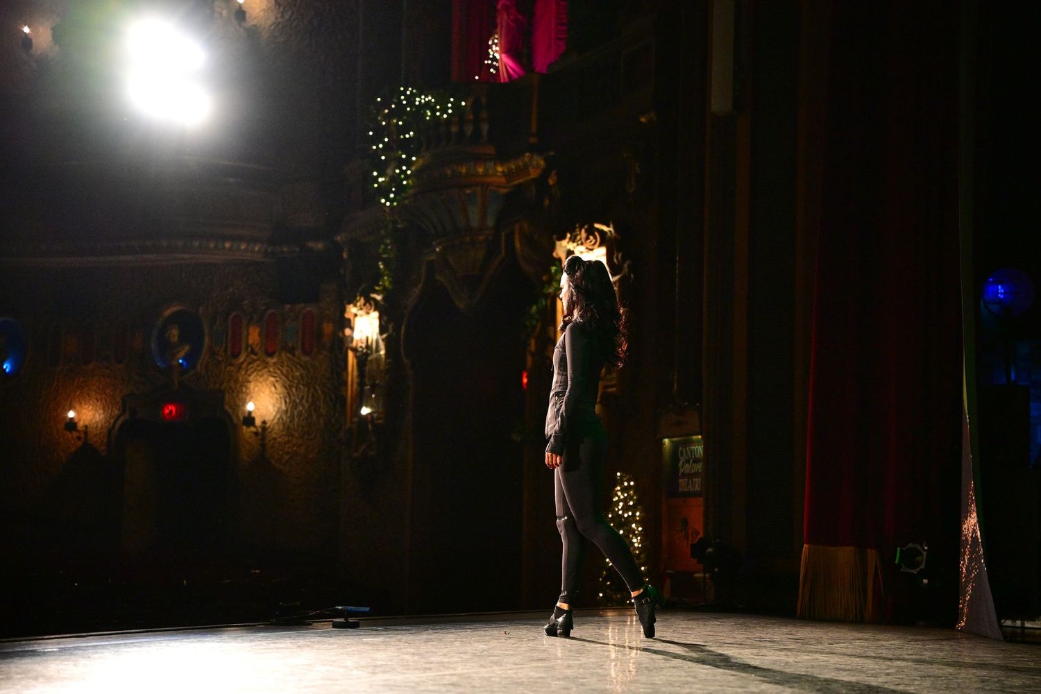 Solo performer executing dramatic dance move in spotlight on dark stage.