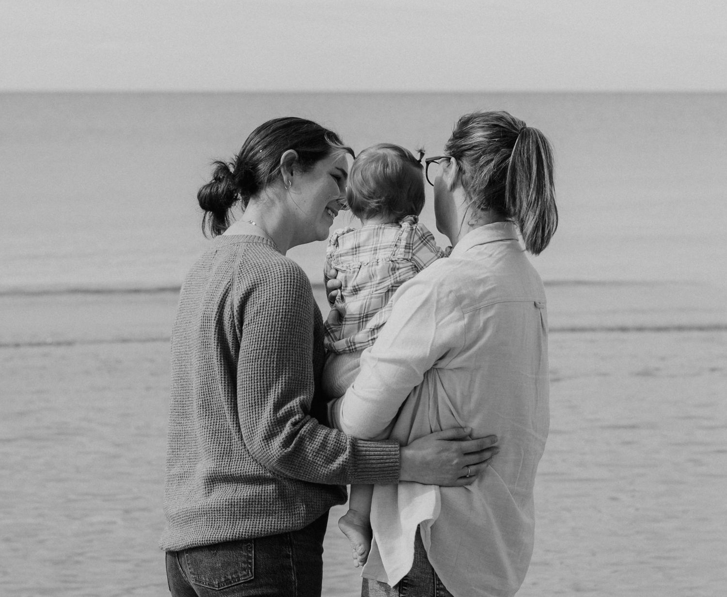 Black and white photo sequence of couple embracing by the ocean.
