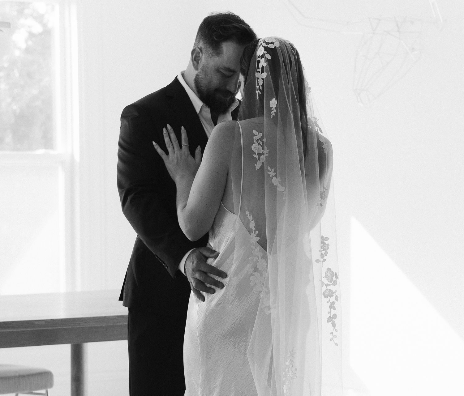 Black and white photo of a bride and groom sharing an intimate kiss on their wedding day.