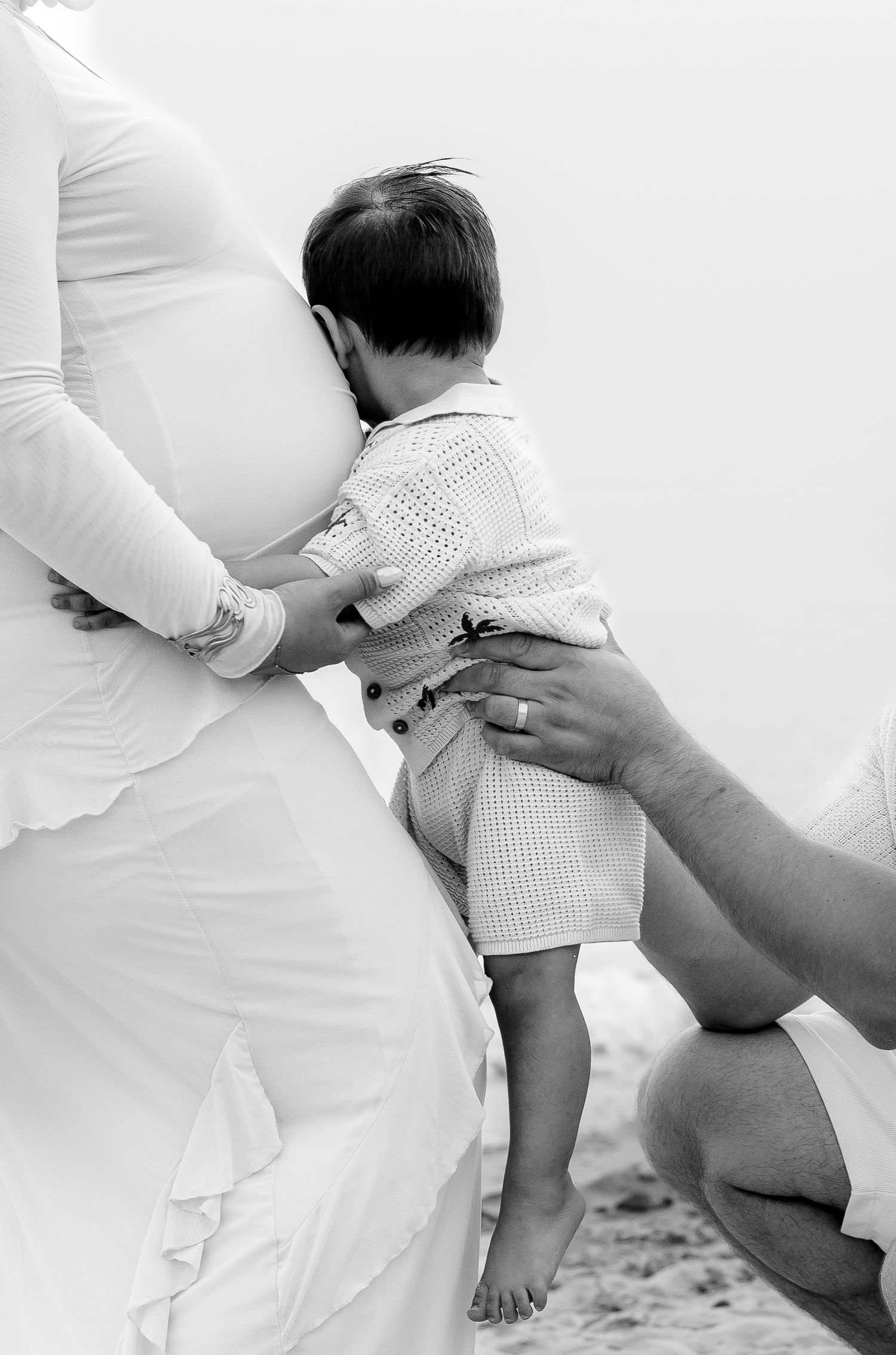 A series of black and white photos showing gentle interactions between parent and baby's feet against white fabric.
