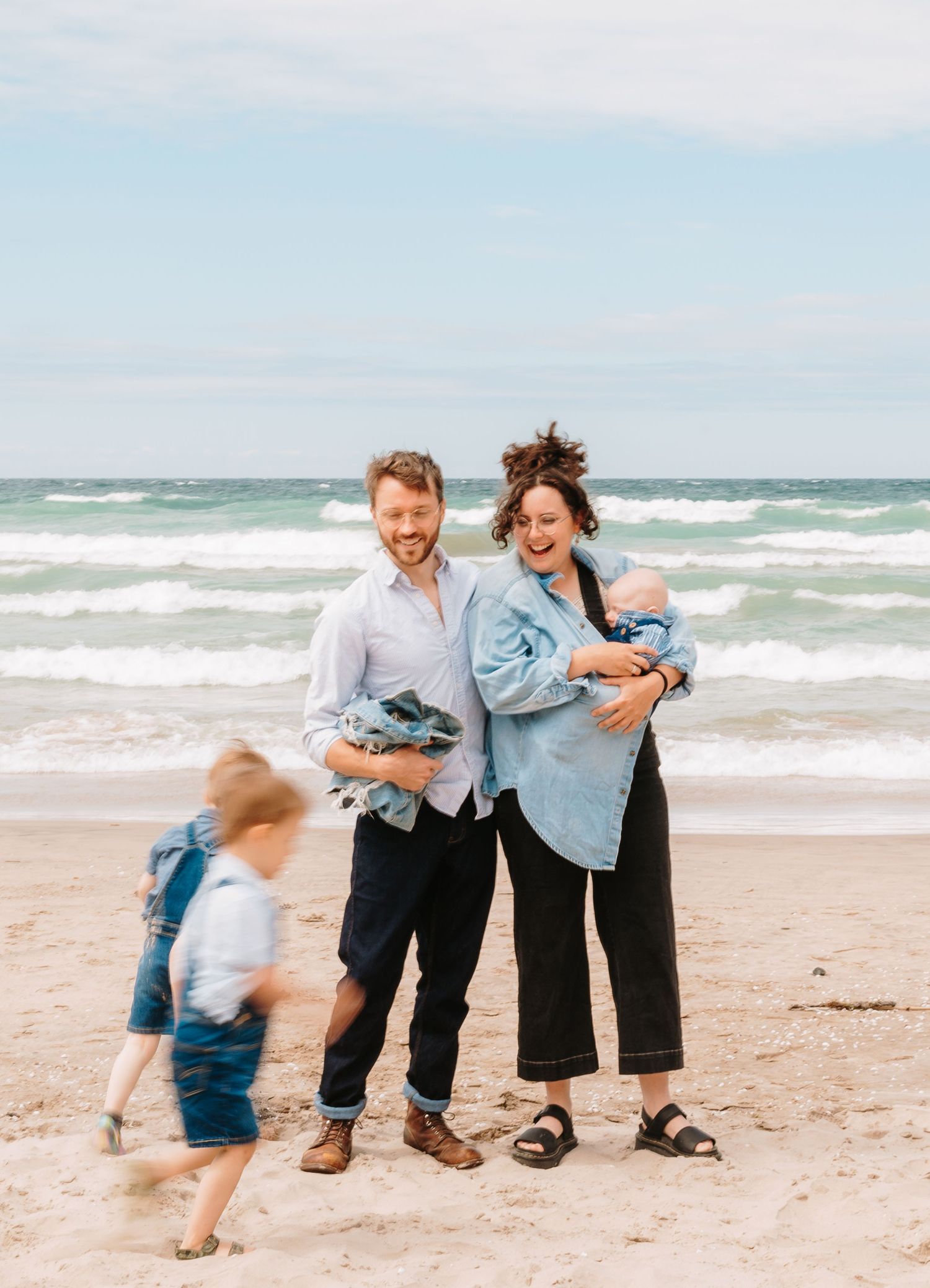 A joyful family moment captured on the beach with waves crashing in the background.